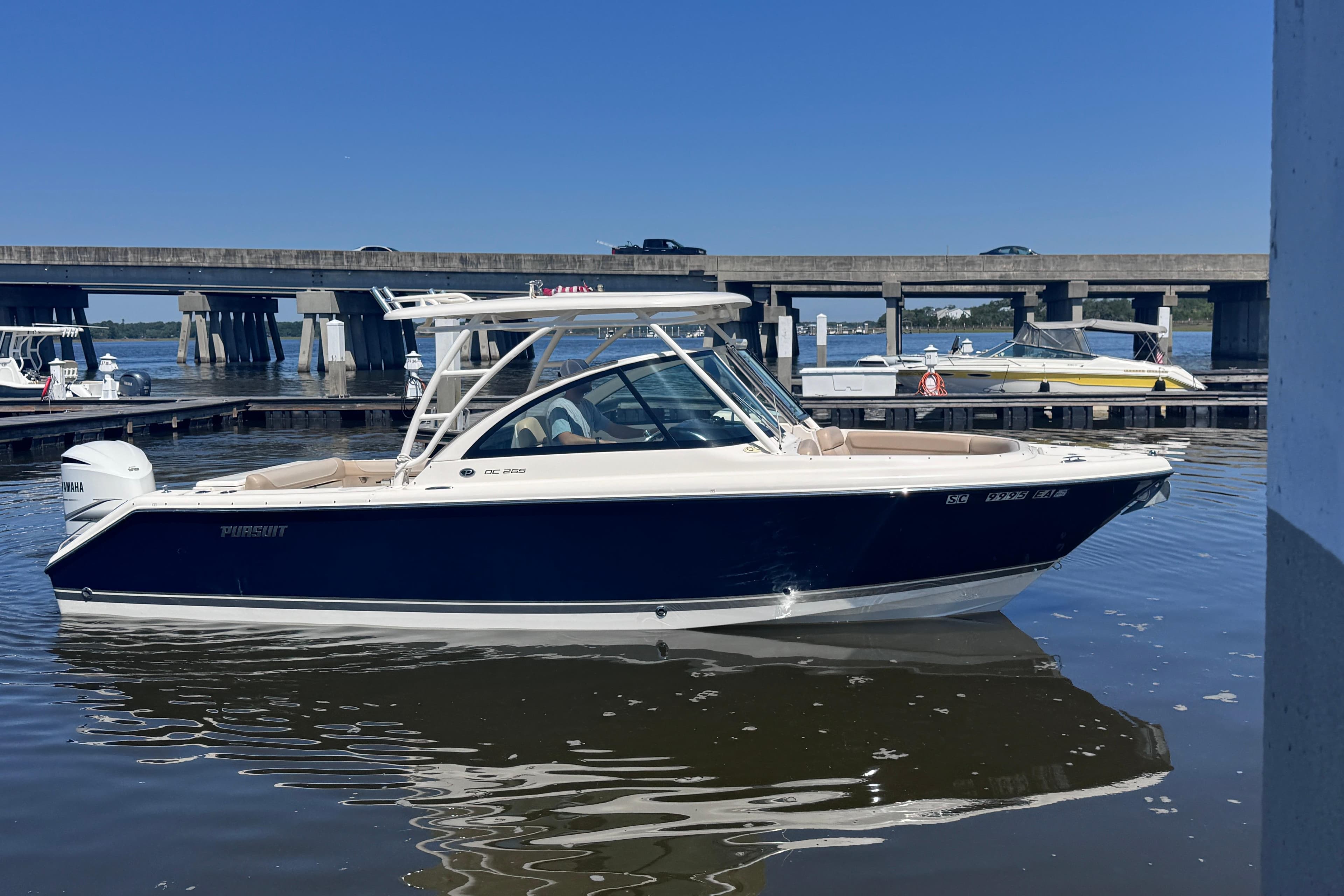 2011 Pursuit DC 265 Dual Console boat docked on calm water under a clear blue sky.