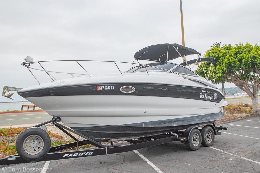 2004 Crownline 250 CR boat on trailer, parked near waterfront, overcast sky.
