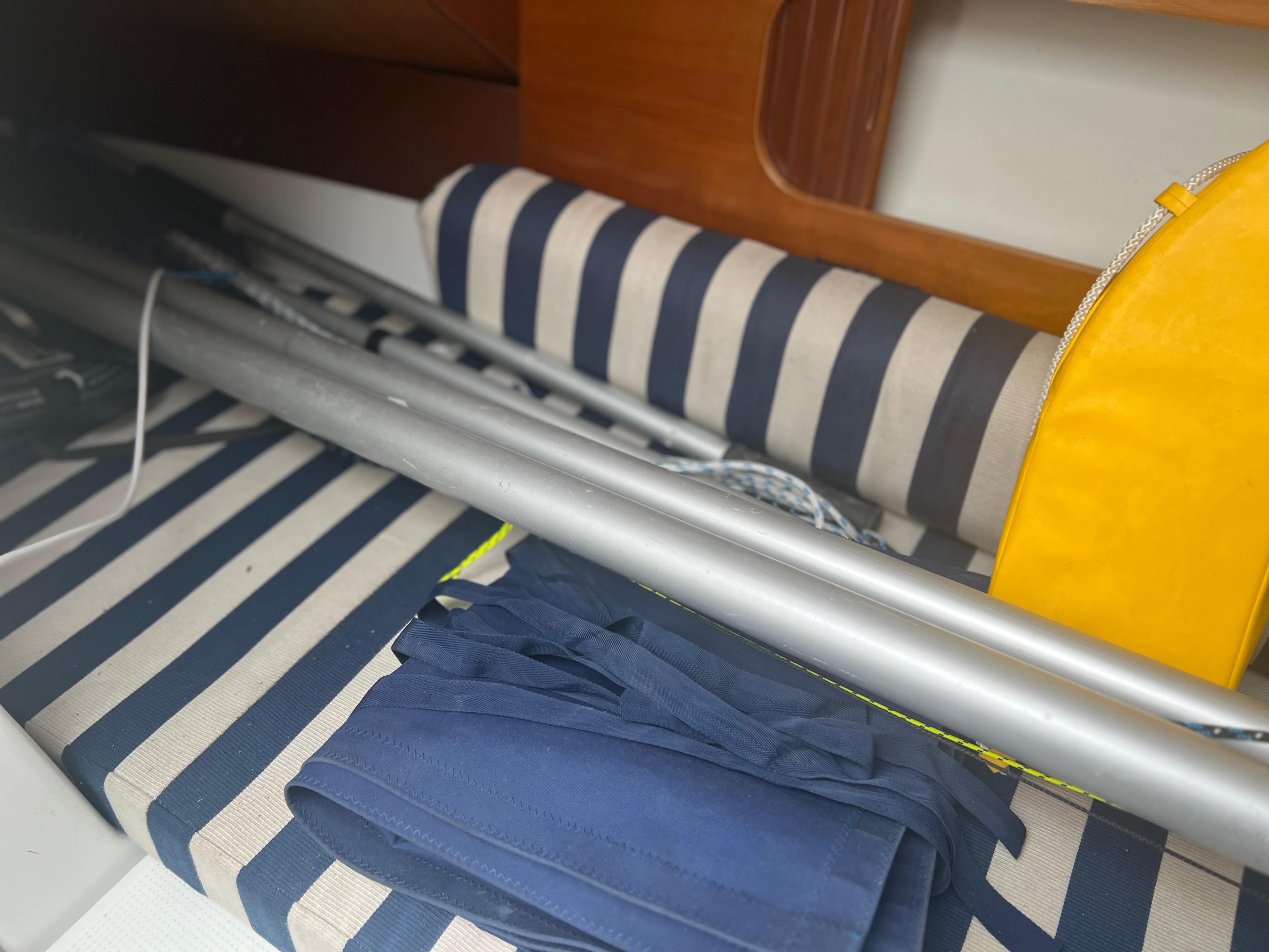 Interior of 2004 Beneteau First 211 sailboat with striped cushions and sailing gear.