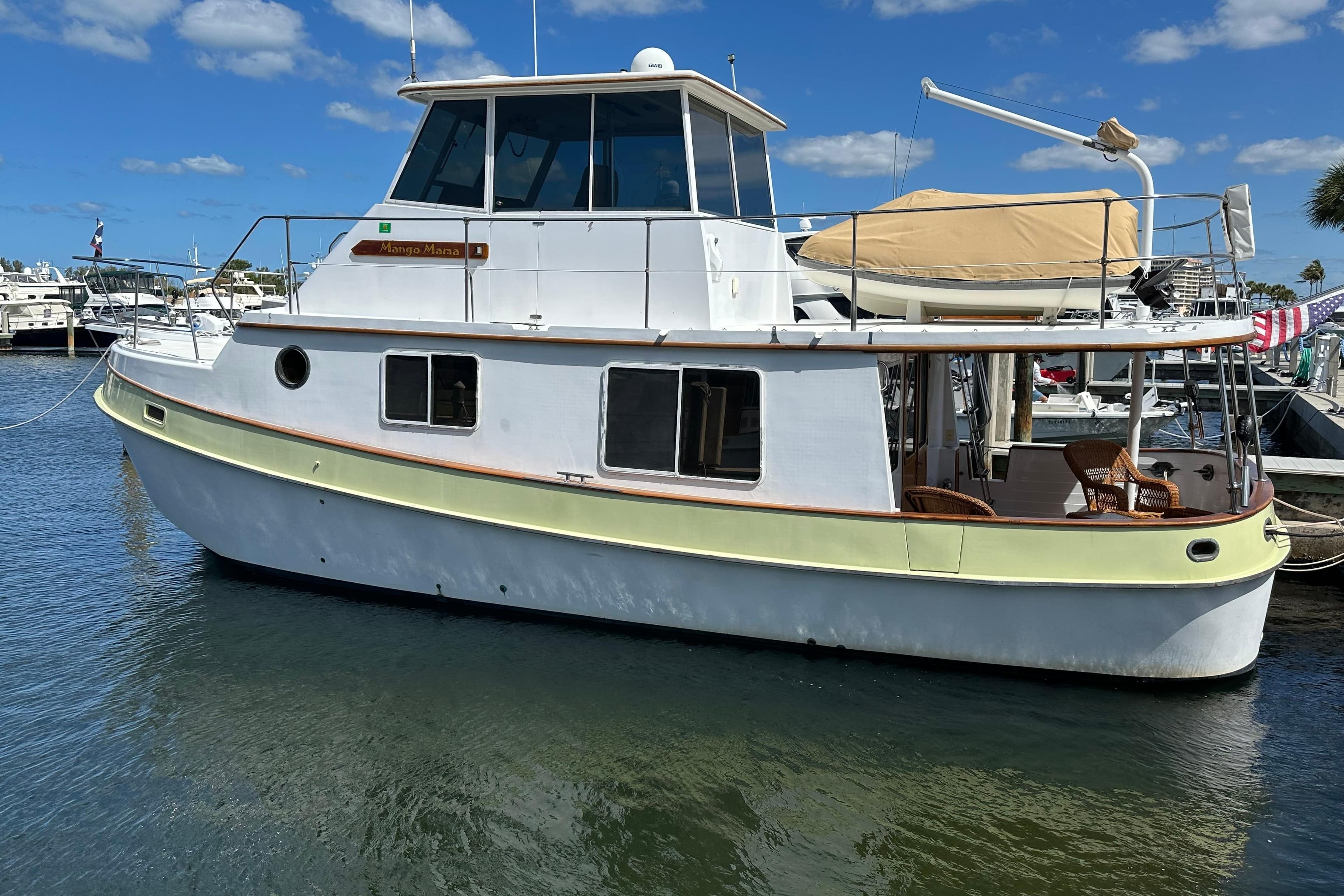 1987 Kadey-Krogen Manatee 36 boat docked in a marina under a clear blue sky.