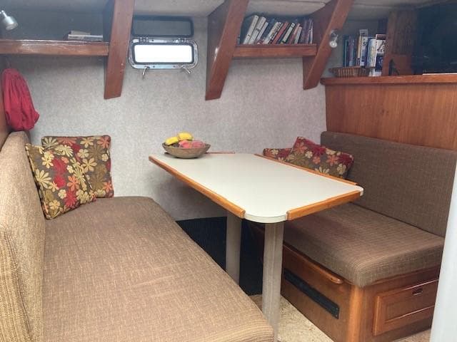 Cozy interior of 1980 Cooper 416 Pilothouse with dining area and bookshelves.