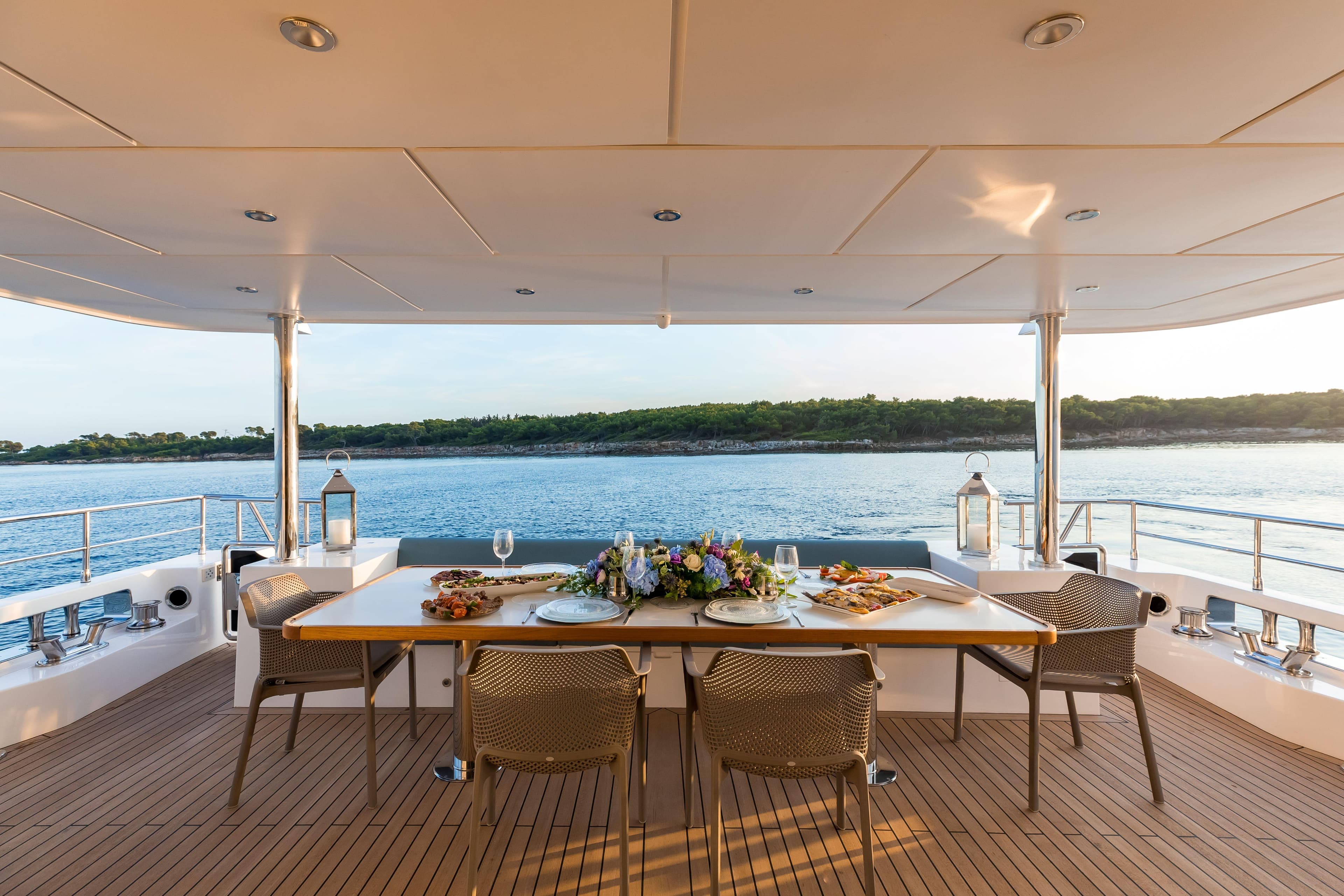 Luxury dining setup on 2025 Nomad 95 SUV yacht, overlooking serene waters.