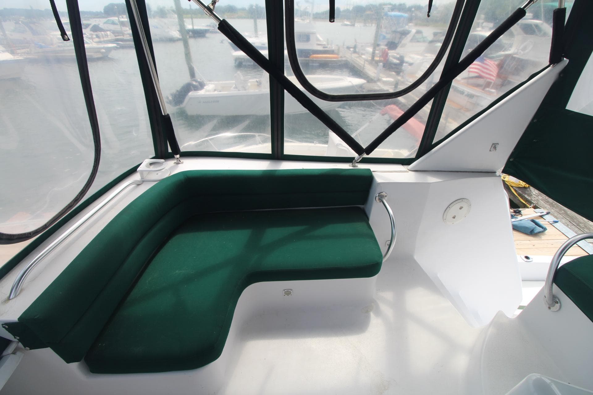 1999 Mainship 31 Sedan Bridge interior with green seating and marina view.
