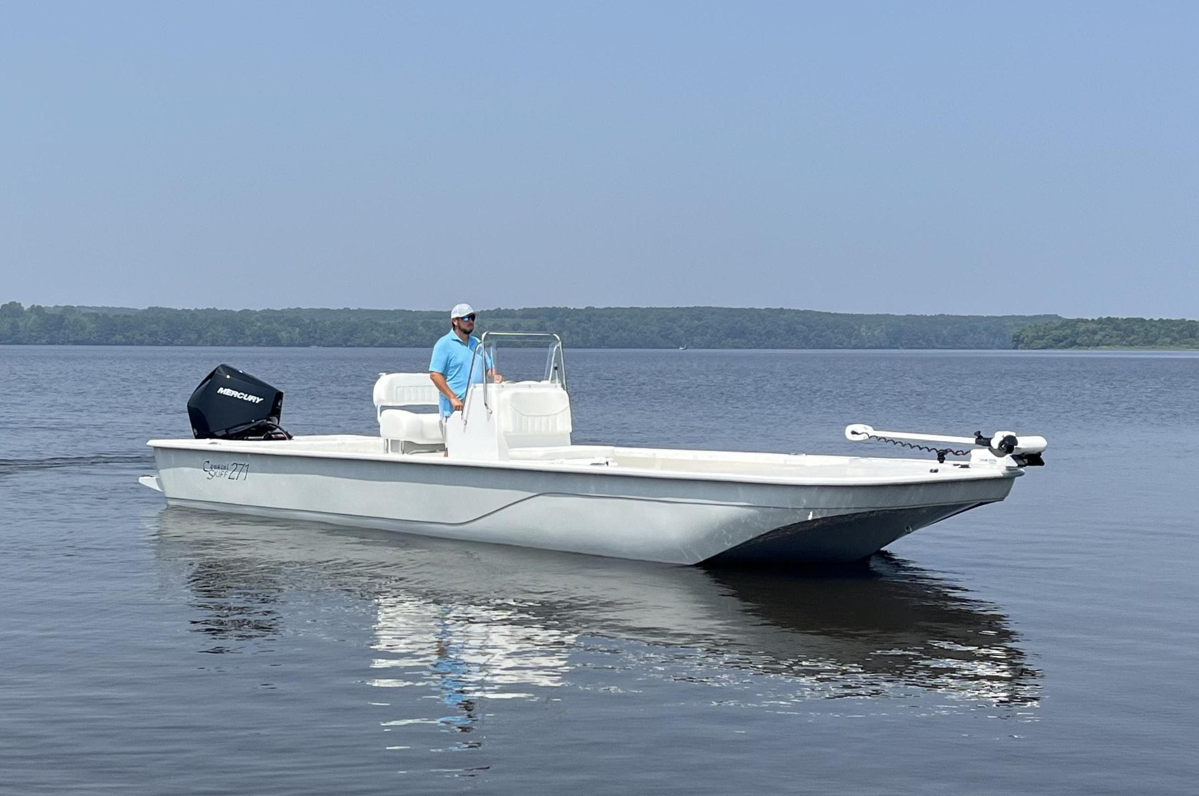 2024 Coastal Skiff 271 boat on calm water with a person at the helm.