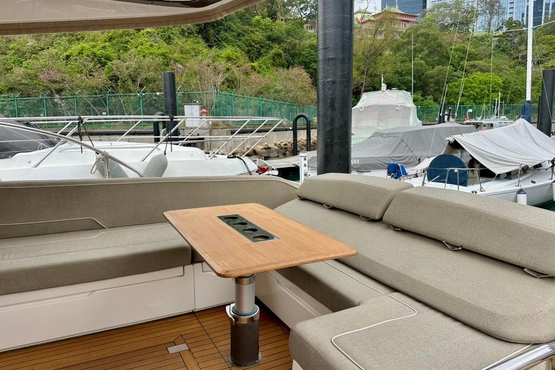 Luxurious seating area on 2019 Fairline Squadron 53 yacht, docked with scenic greenery.