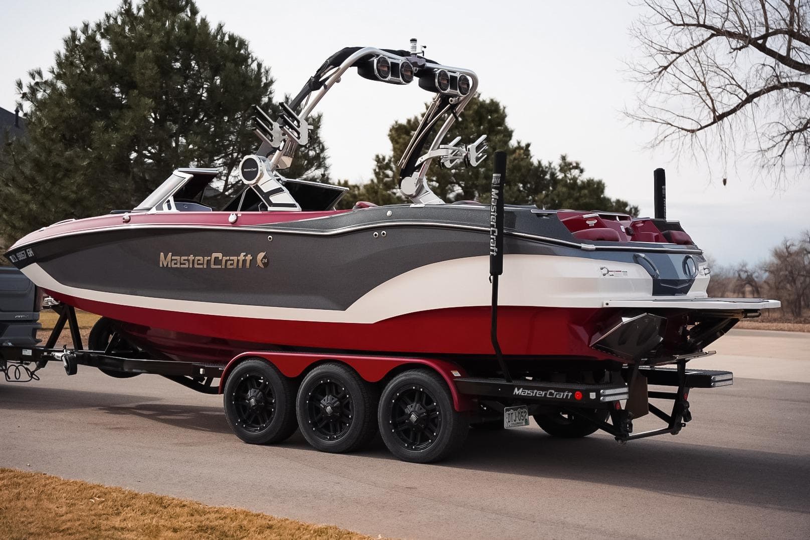 2019 MasterCraft X24 boat on trailer, parked outdoors, showcasing sleek design and vibrant colors.