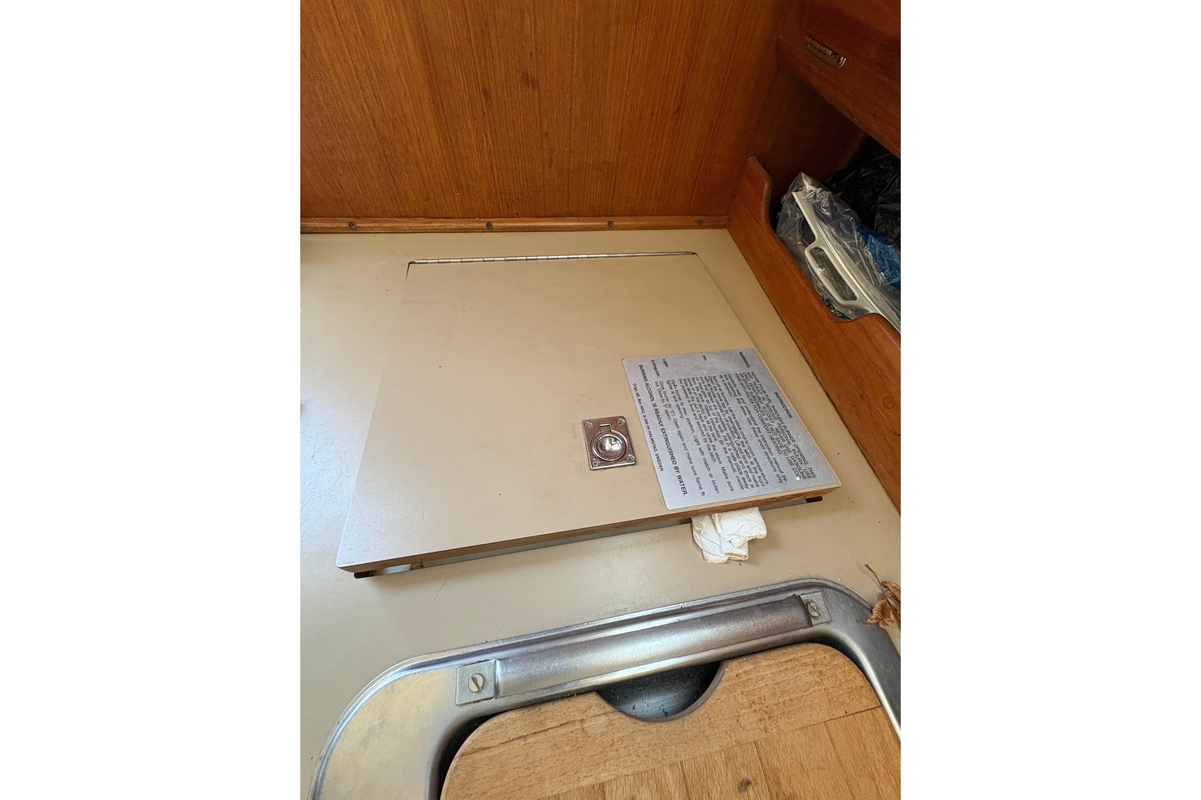 Floor hatch inside a 1993 Hunter 28 sailboat, featuring a metal latch and wooden interior.