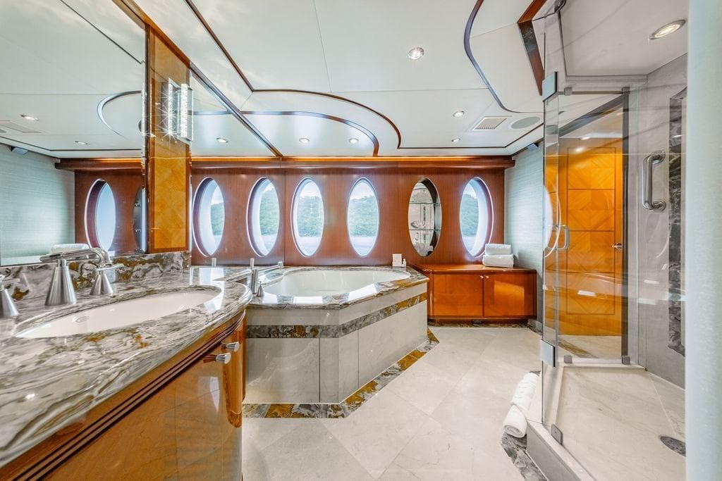 Luxurious yacht bathroom with marble finishes, oval windows, and modern fixtures on Ares Custom Marine 141.
