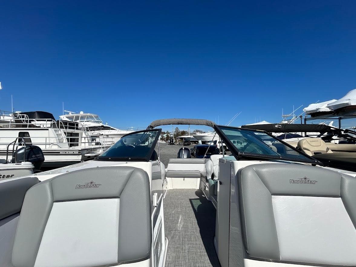 2022 NauticStar 243DC Sport Deck boat at a marina under clear blue skies.