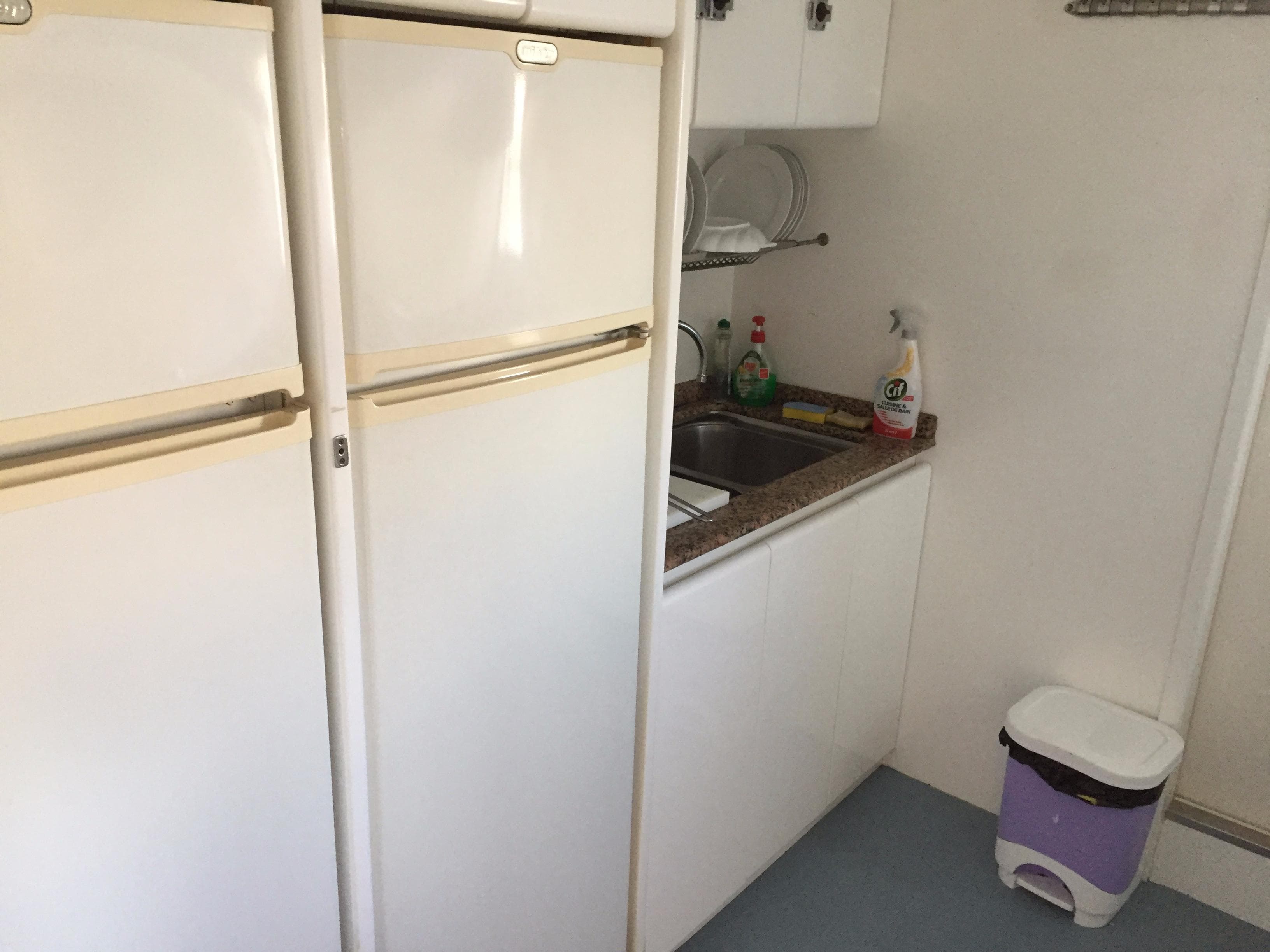 Compact kitchen with dual refrigerators, sink, and cleaning supplies; Falcon 76 model, 1994.
