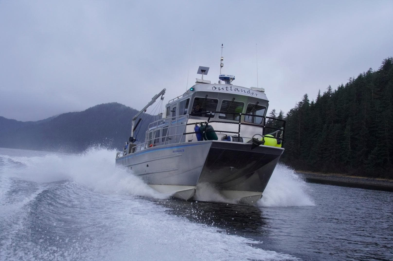 2007 Armstrong Marine 36 Catamaran cruising through water with forested hills in background.
