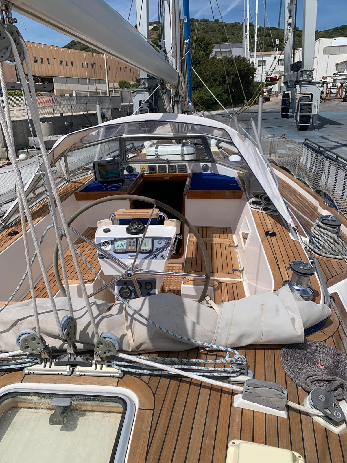 2006 Hallberg-Rassy 48 MK sailboat with wooden deck and dual steering wheels in a marina.