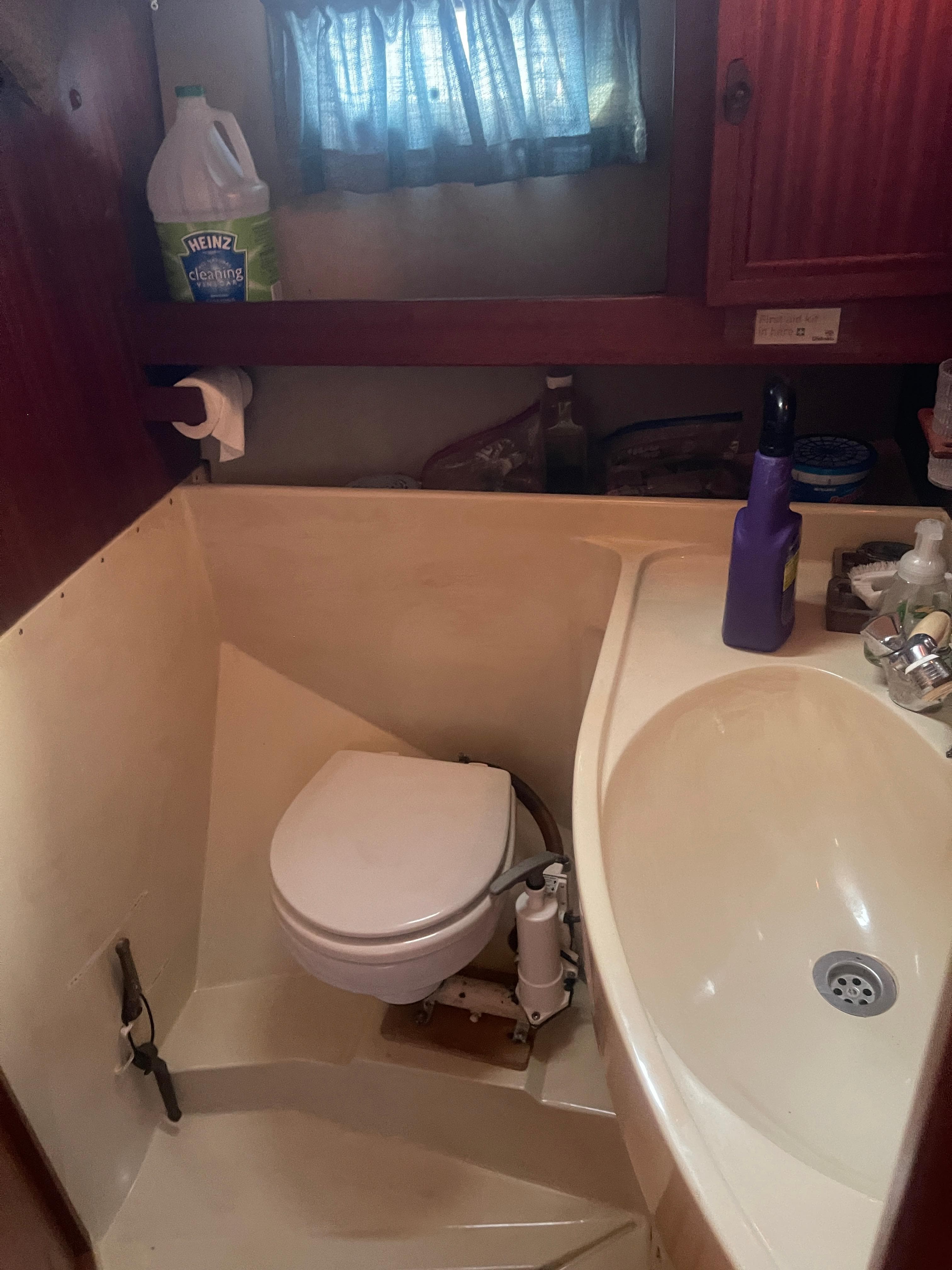 Compact bathroom in a 1984 Hanseat 37 sailboat, featuring a toilet and sink.