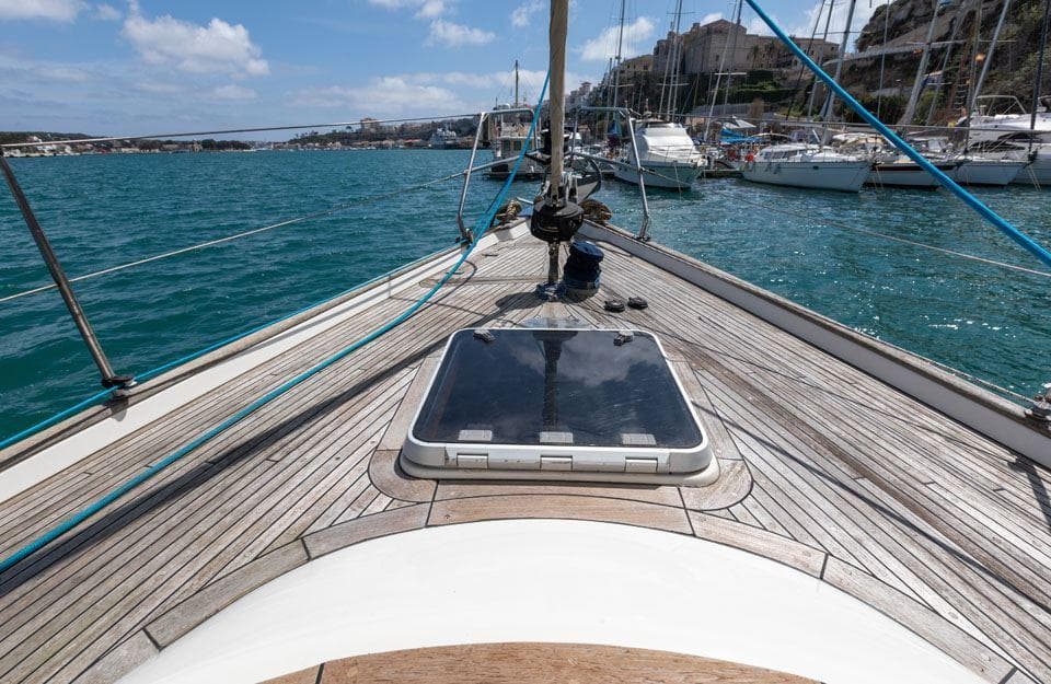 Deck view of 1997 Hallberg-Rassy 42 sailboat in a marina with clear blue water.
