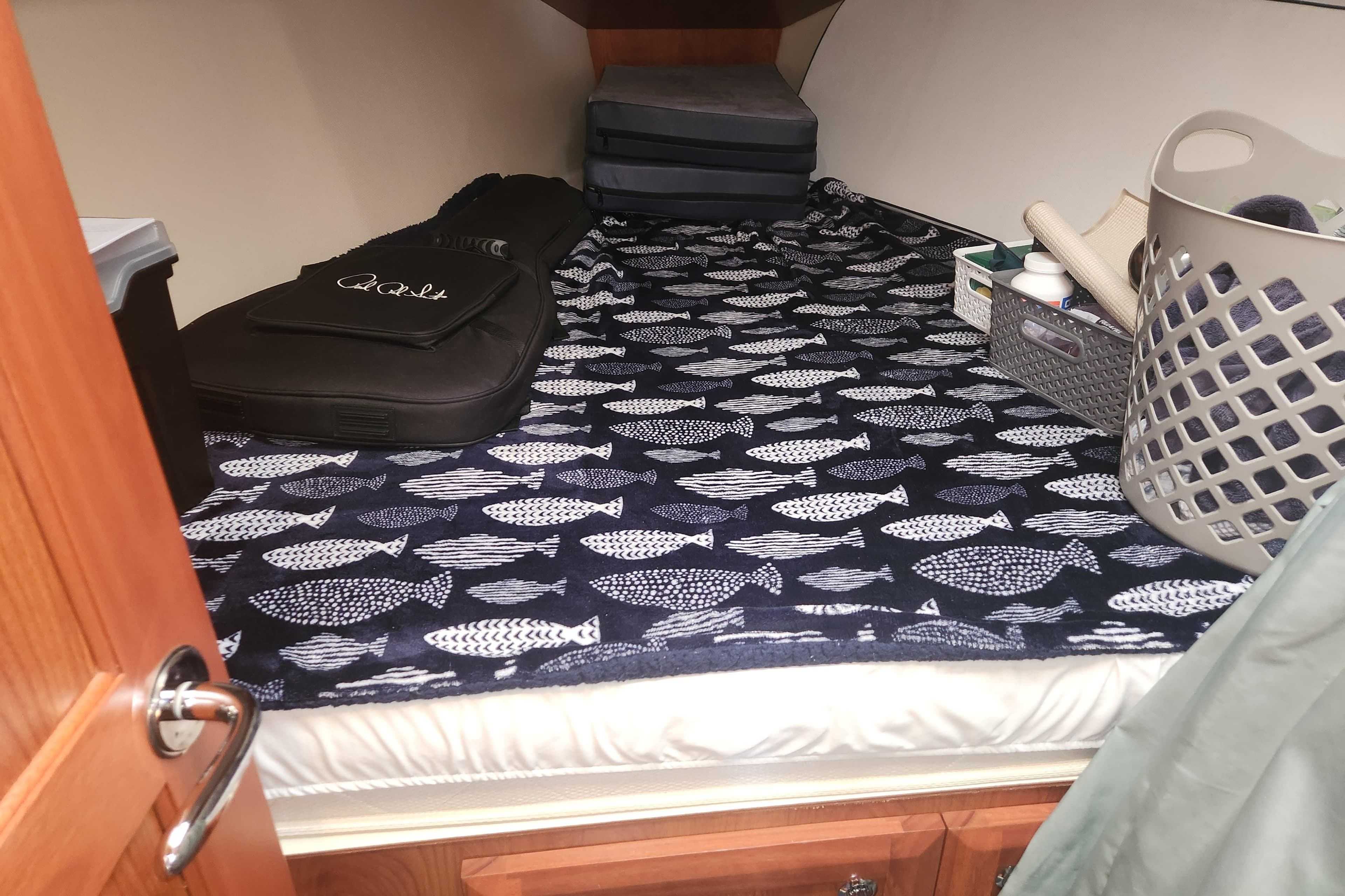 Cozy cabin interior of 2011 Hunter 39 sailboat with fish-patterned bedding and storage items.