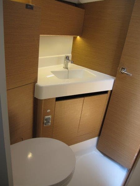2025 Jeanneau Sun Odyssey 350 yacht bathroom with modern sink and wooden cabinetry.