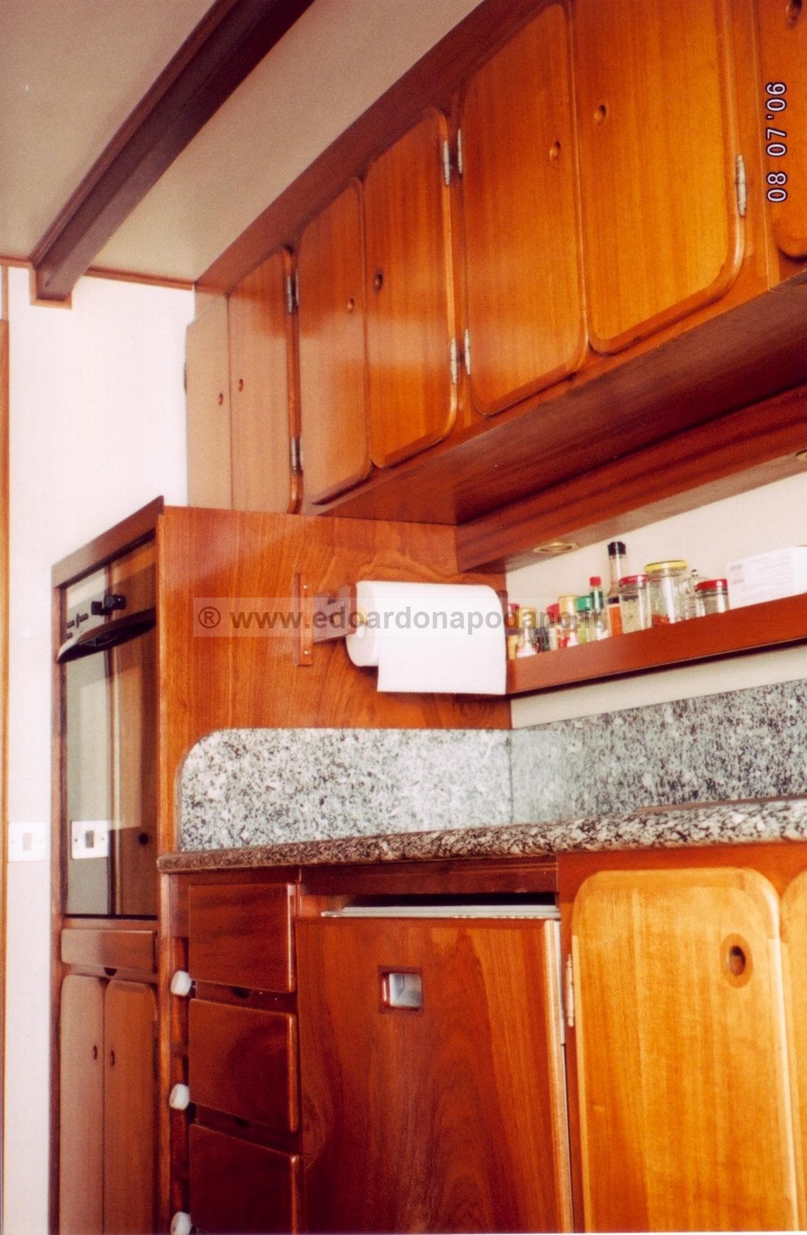Wooden kitchen interior on 1925 Codecasa schooner, featuring cabinets and granite countertop.