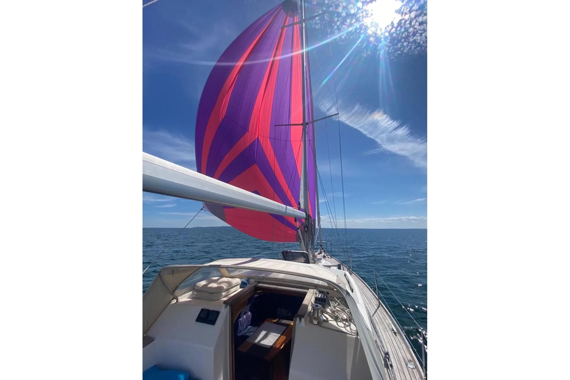 Sailing Nordship 35 DS 1998 with vibrant spinnaker on open sea under sunny sky.