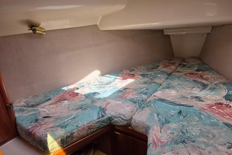 1996 Hunter 336 sailboat cabin with abstract-patterned bedding and wall-mounted light.