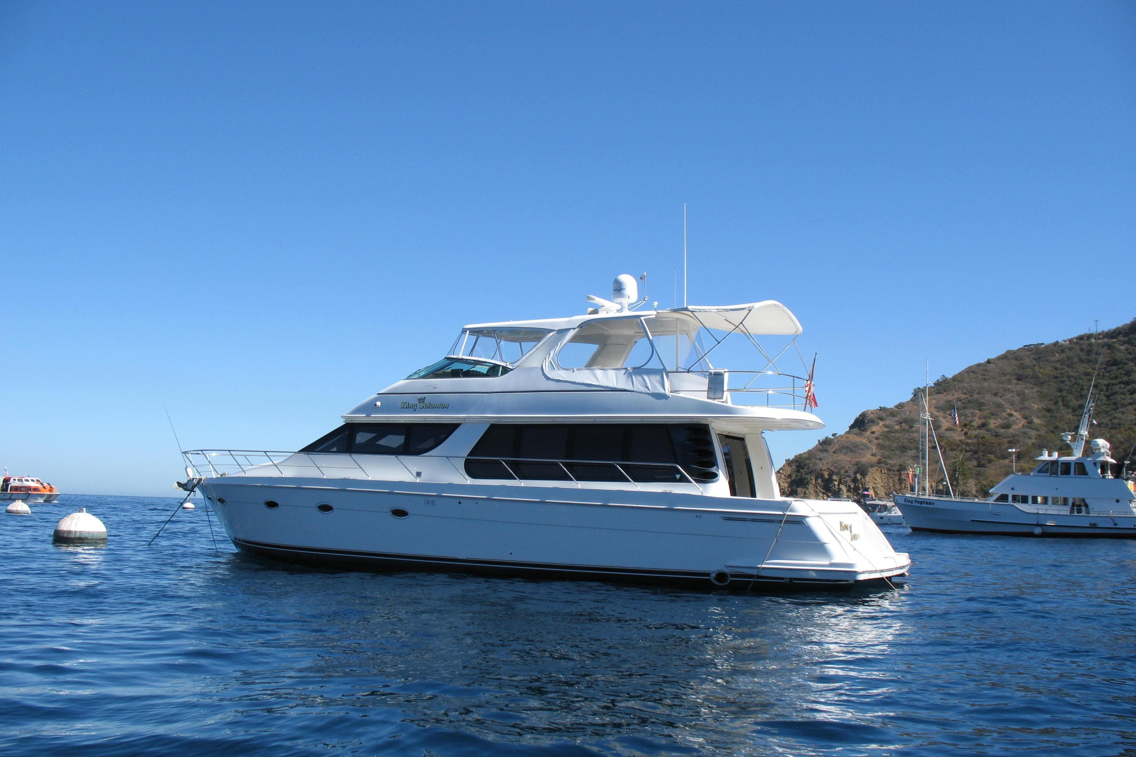 2002 Carver 570 Voyager Pilothouse yacht anchored in scenic coastal waters.
