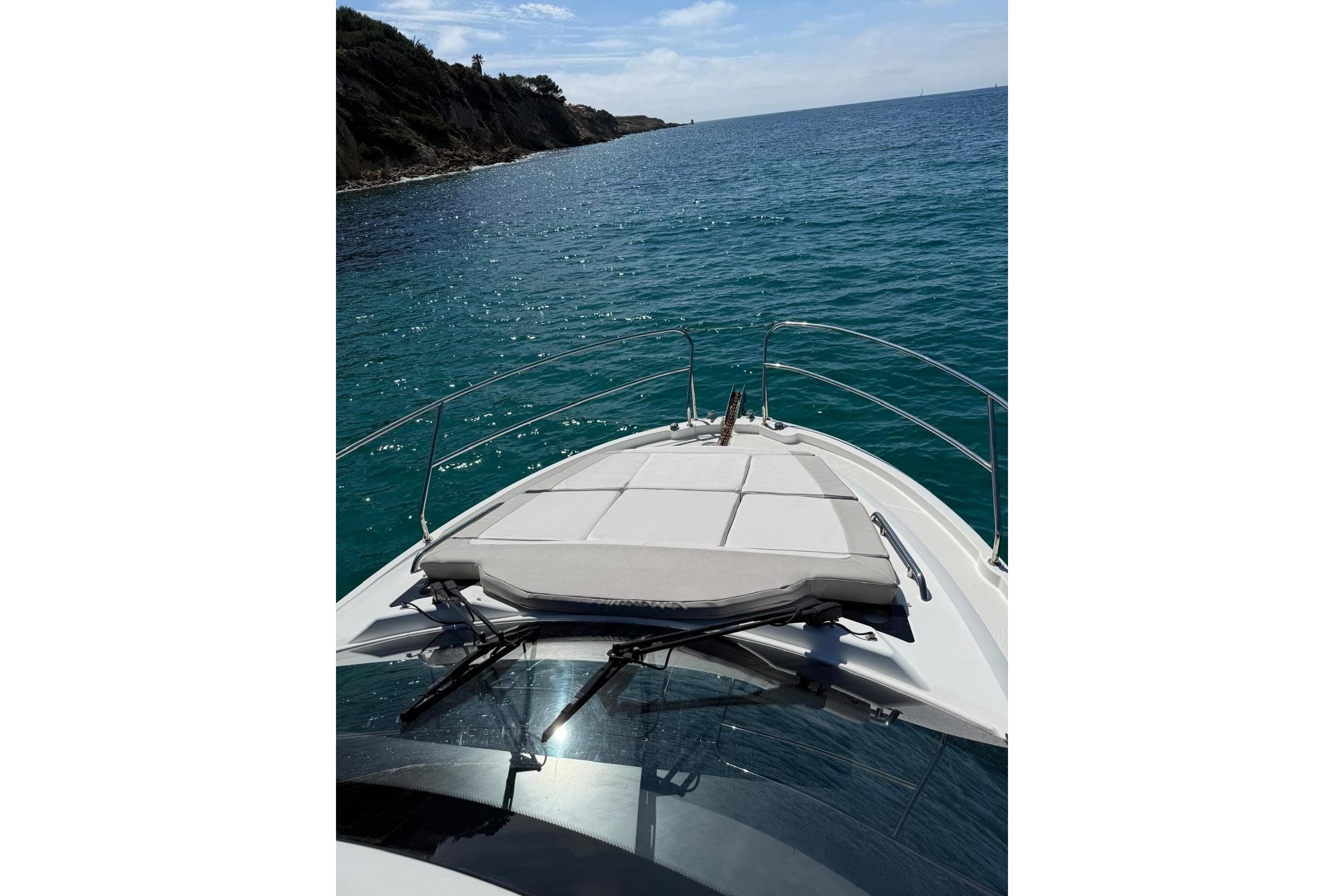 2017 Jeanneau Leader 33 yacht cruising on clear blue waters near a rocky coastline.