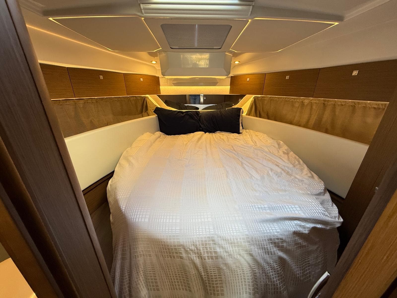 Cozy bedroom interior of 2021 Jeanneau NC Weekender 1095 boat with elegant bedding.