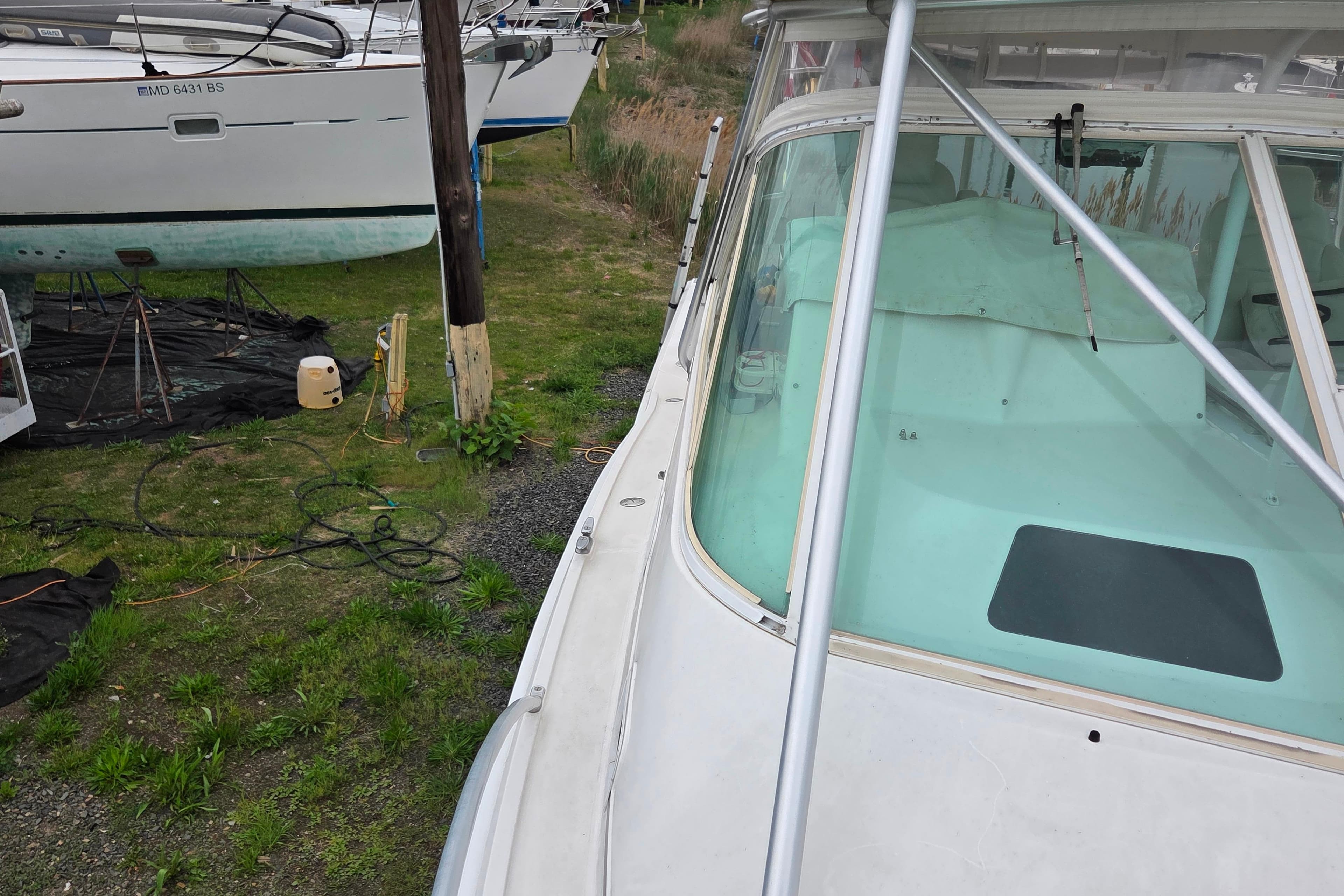 1999 Cabo 35 Express boat on land, near other vessels, with visible windshield and deck.