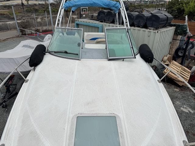 2006 Bayliner 265 SD boat on land, with open windshield and protective covers.