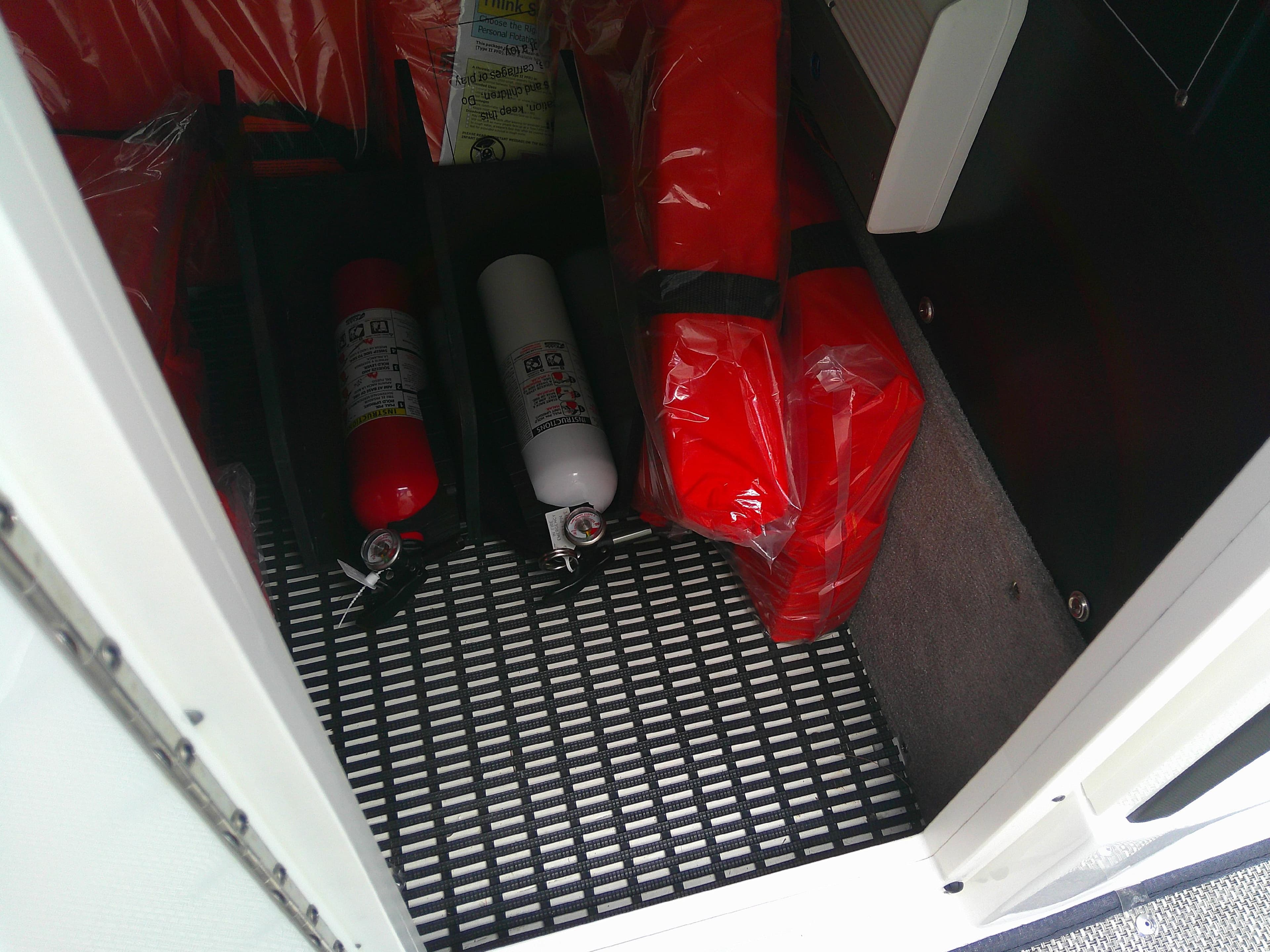 Safety equipment storage on 2020 Monterey 305 Super Sport boat, featuring fire extinguishers and life jackets.