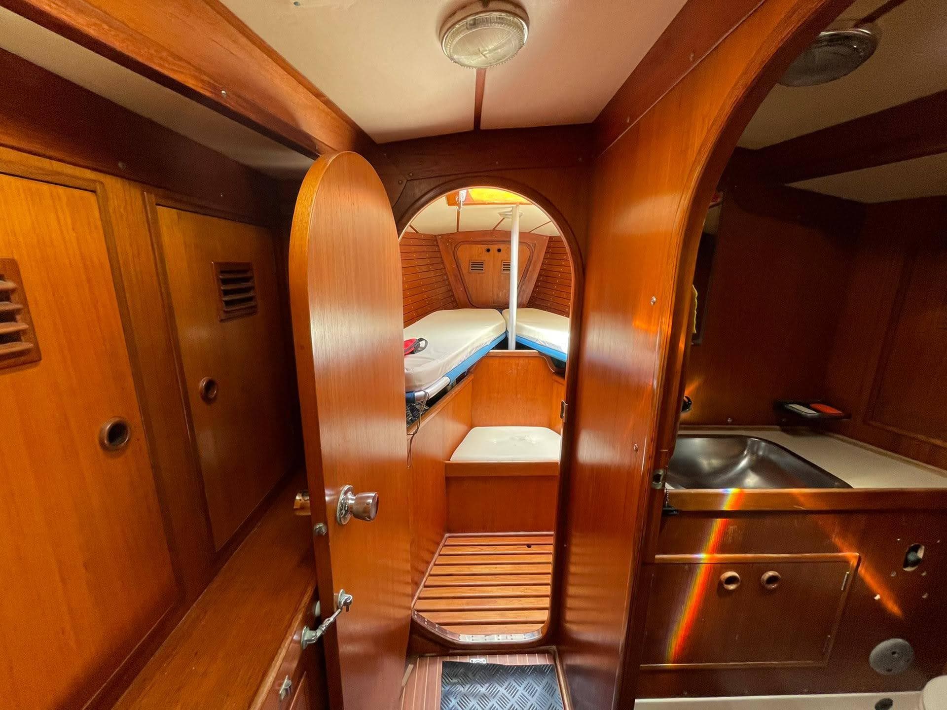 Interior of 1977 Nautor Swan 411 yacht, featuring wooden cabinetry and cozy sleeping quarters.