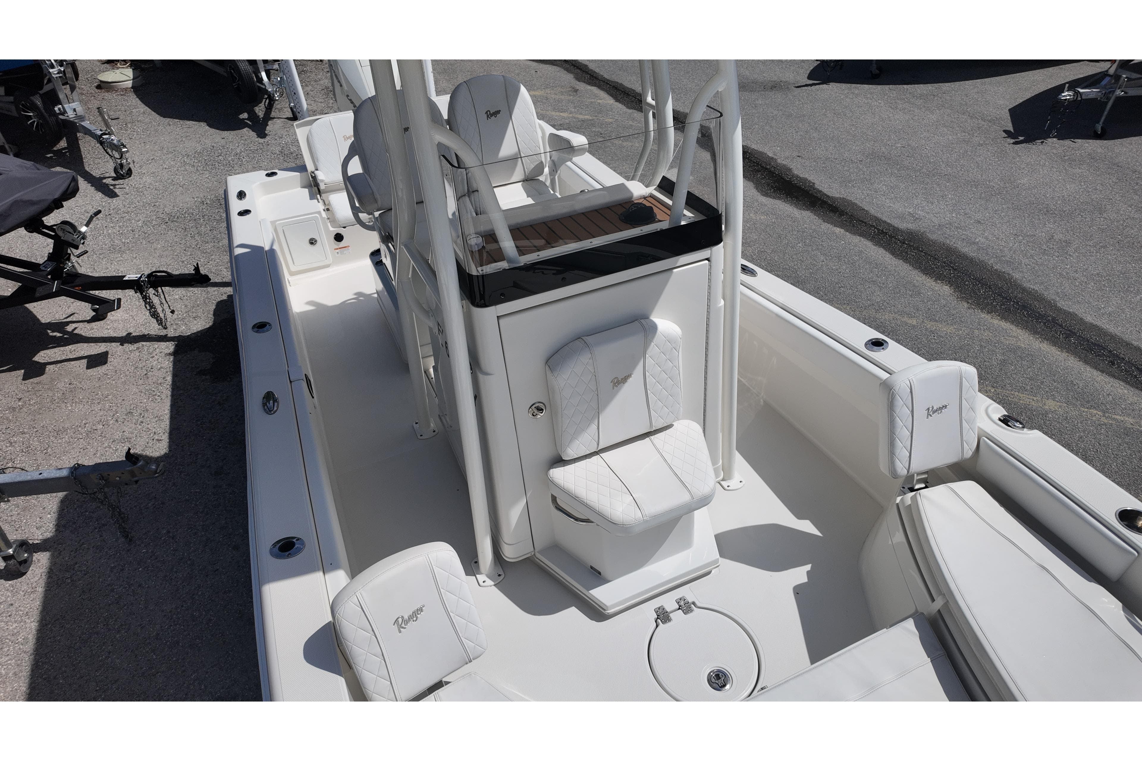 2024 Ranger 2660 Bay boat interior with white seating and console, parked on pavement.