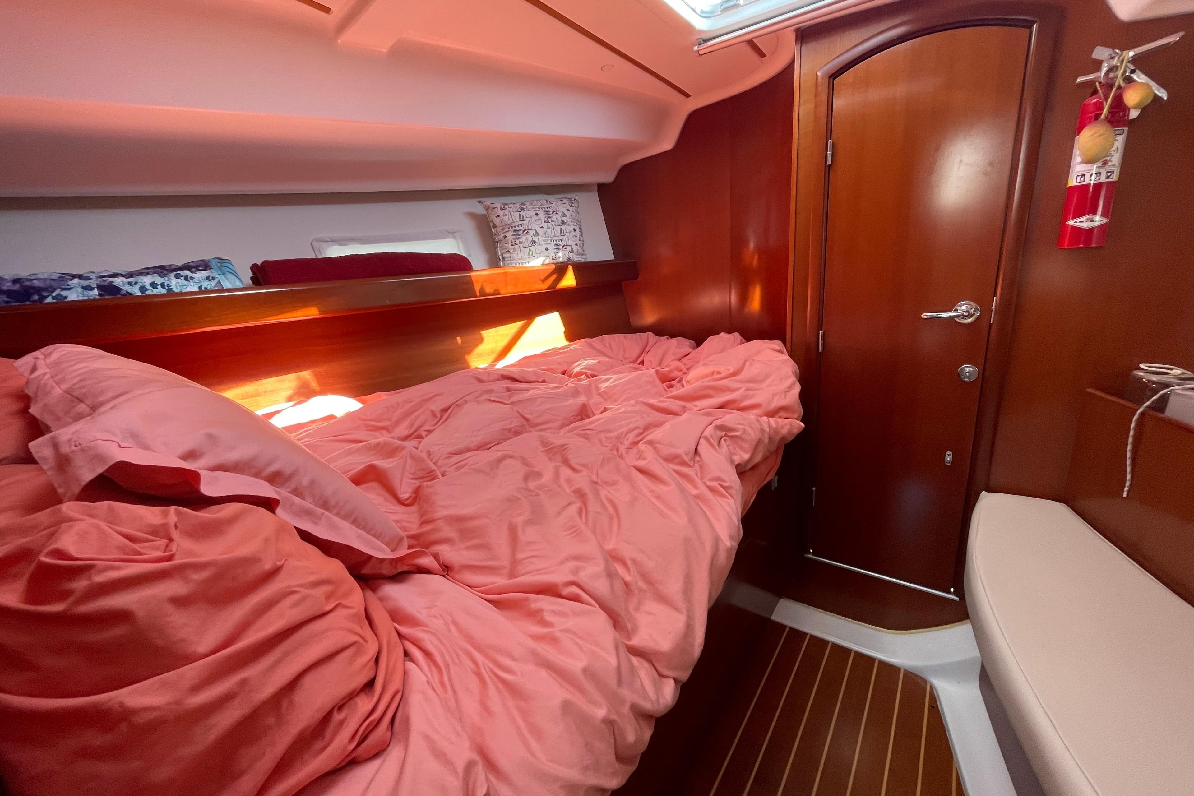 Cozy cabin interior of 2007 Beneteau 393 sailboat with pink bedding and wooden accents.