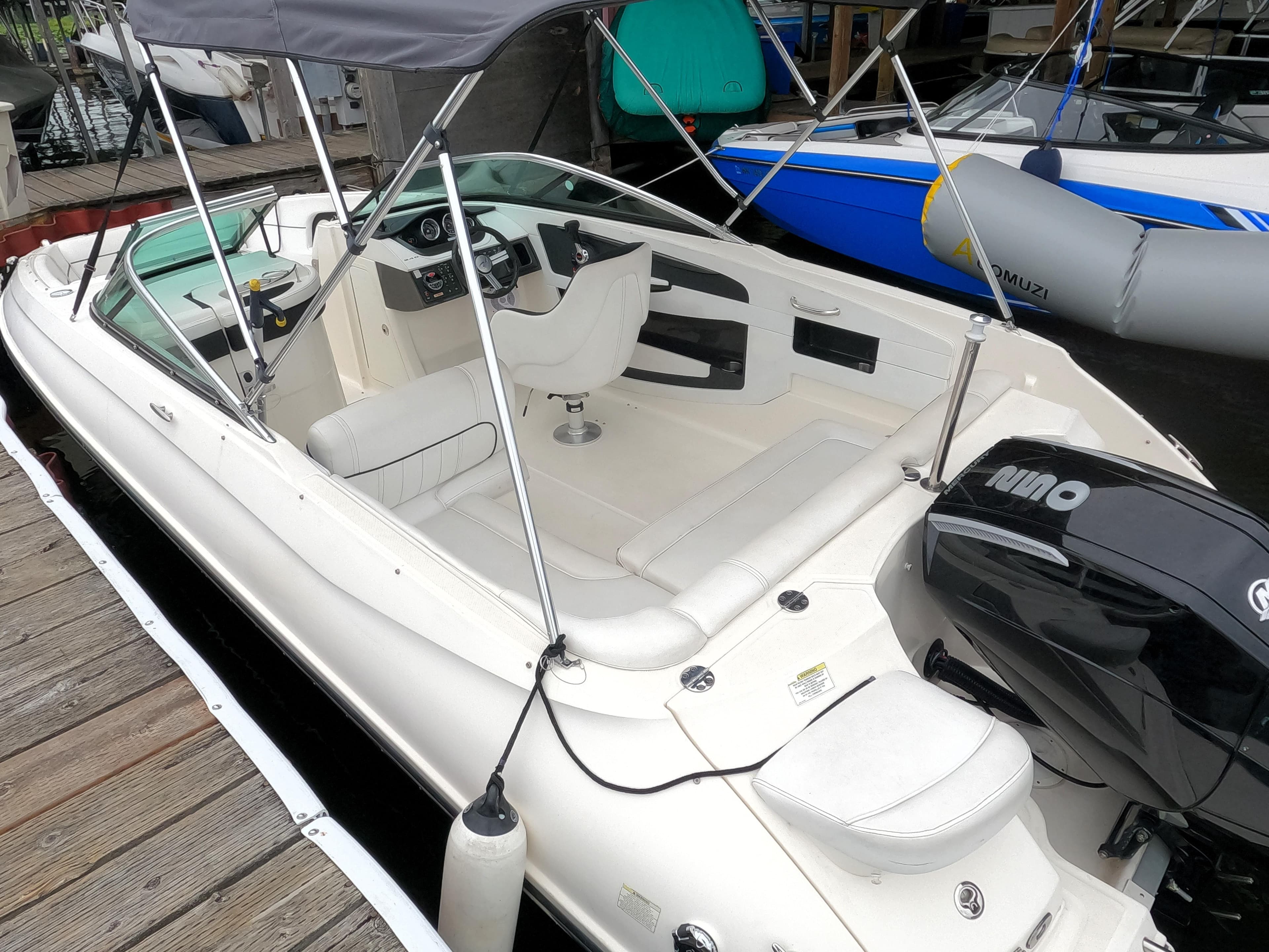 2014 Sea Ray 240 Sundeck Outboard boat docked, featuring spacious seating and a Bimini top.
