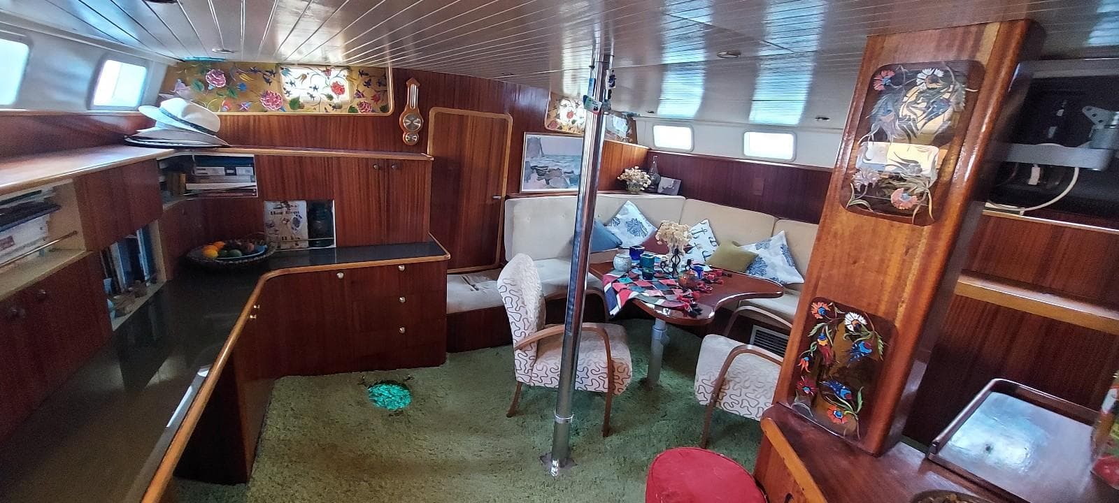 Interior of a 1976 CNSO MIKADO 56 Ketch yacht with wooden furnishings and cozy seating area.