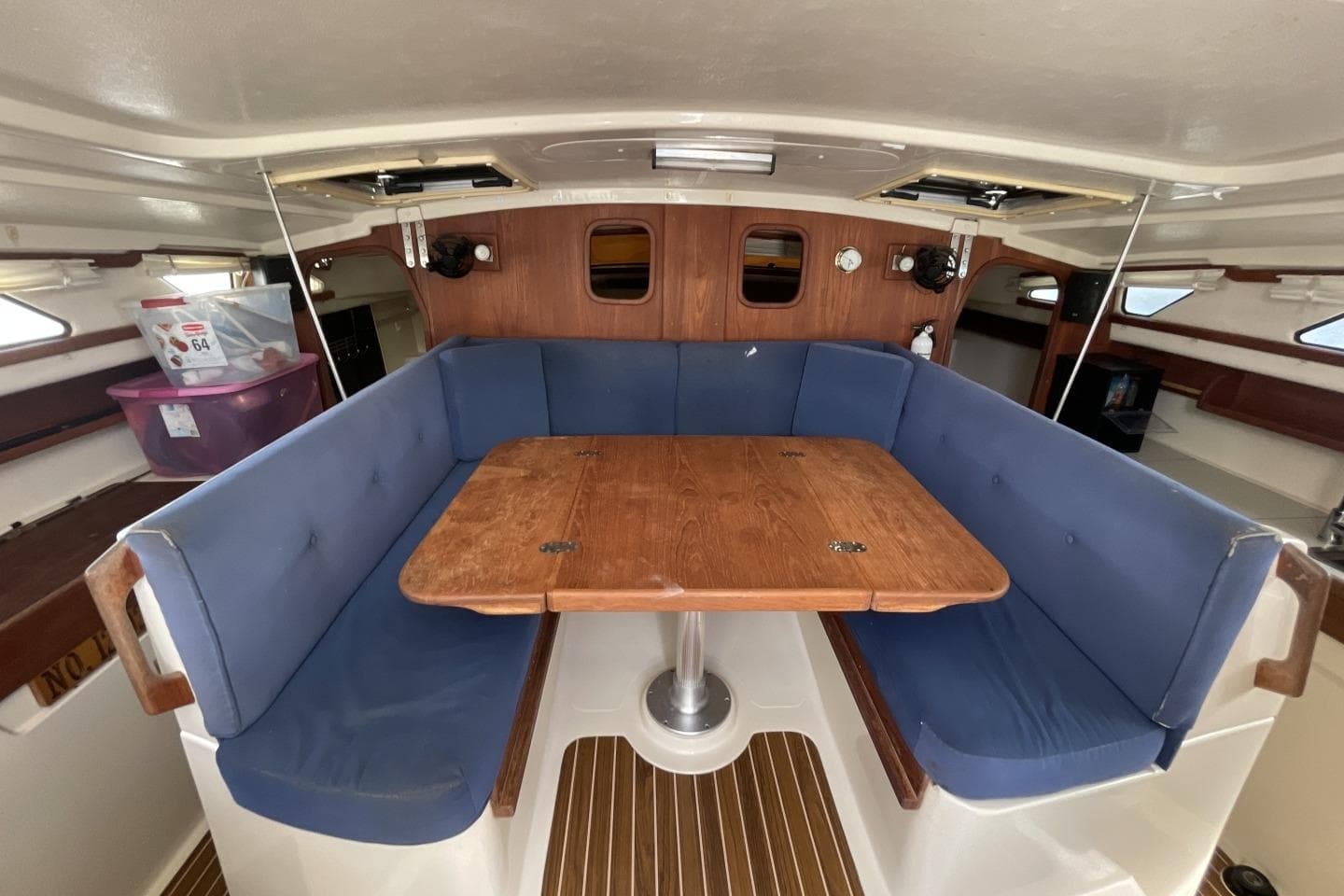 Interior of 2008 Gemini 105Mc sailboat with blue cushioned seating and wooden table.