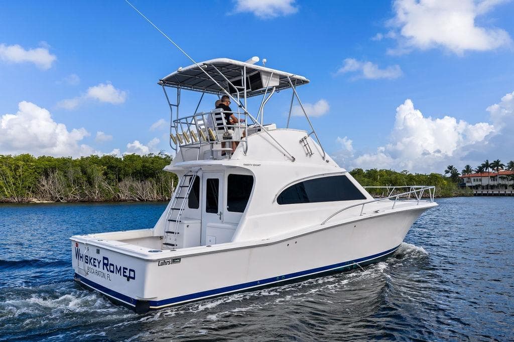 2005 Luhrs 38 Convertible yacht cruising on a sunny day, with lush greenery in the background.