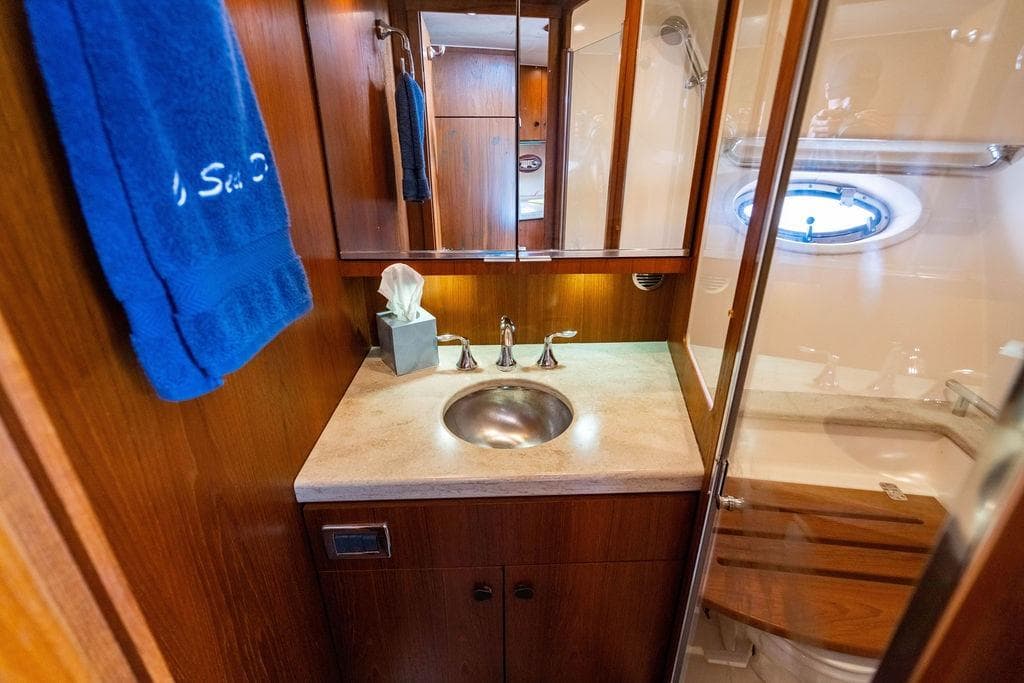 Luxurious bathroom interior of 2013 Tiara Yachts 3600 Coronet with wood accents and porthole.