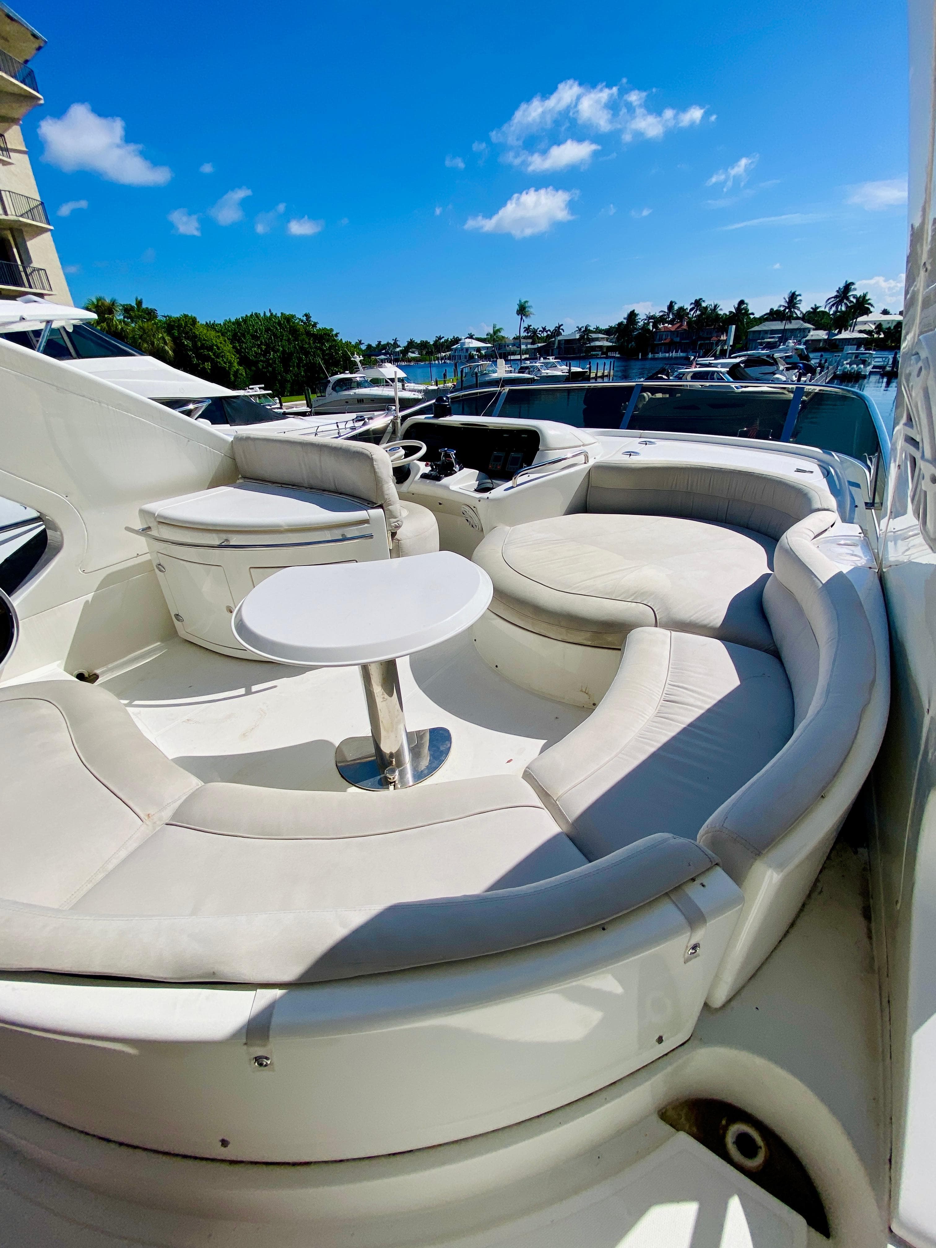 Luxurious 2002 Azimut 55 yacht with elegant seating area and table, docked under a clear blue sky.