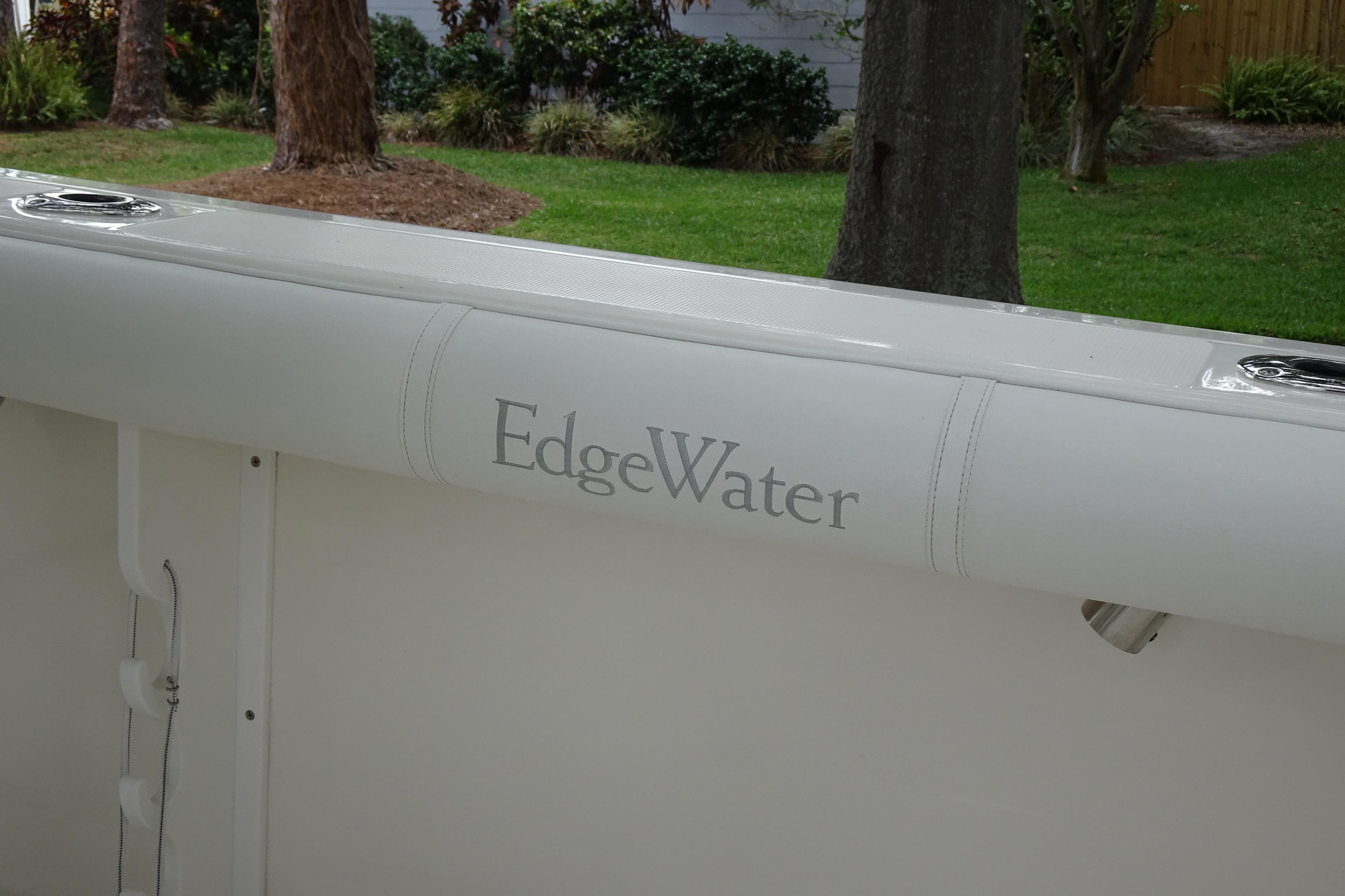 2006 Edgewater 265CC boat interior with logo, surrounded by lush greenery.