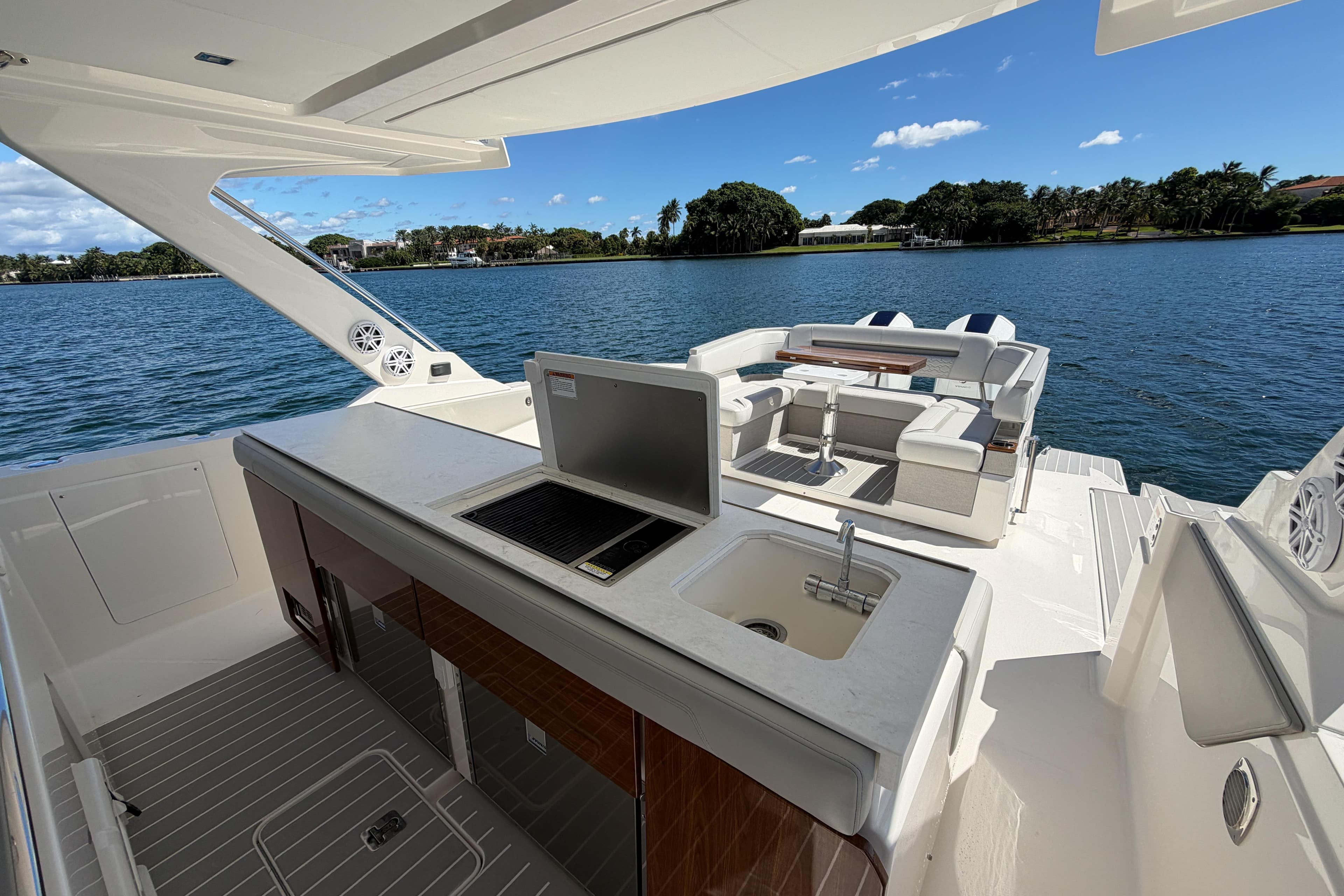 2024 Tiara Yachts 43 LS luxury yacht interior with seating and kitchenette, overlooking serene water.