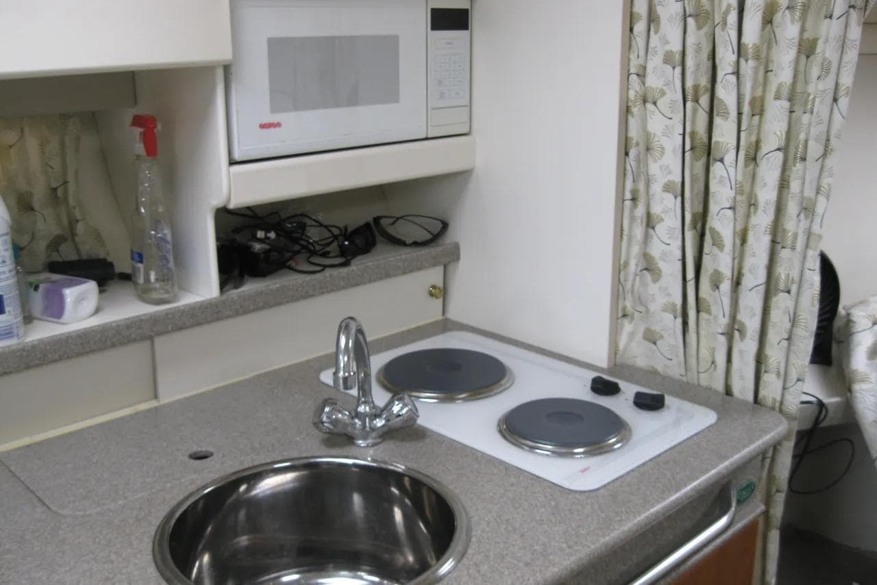 Compact kitchen area in a 2000 Formula 31 Performance Cruiser with stove, sink, and microwave.