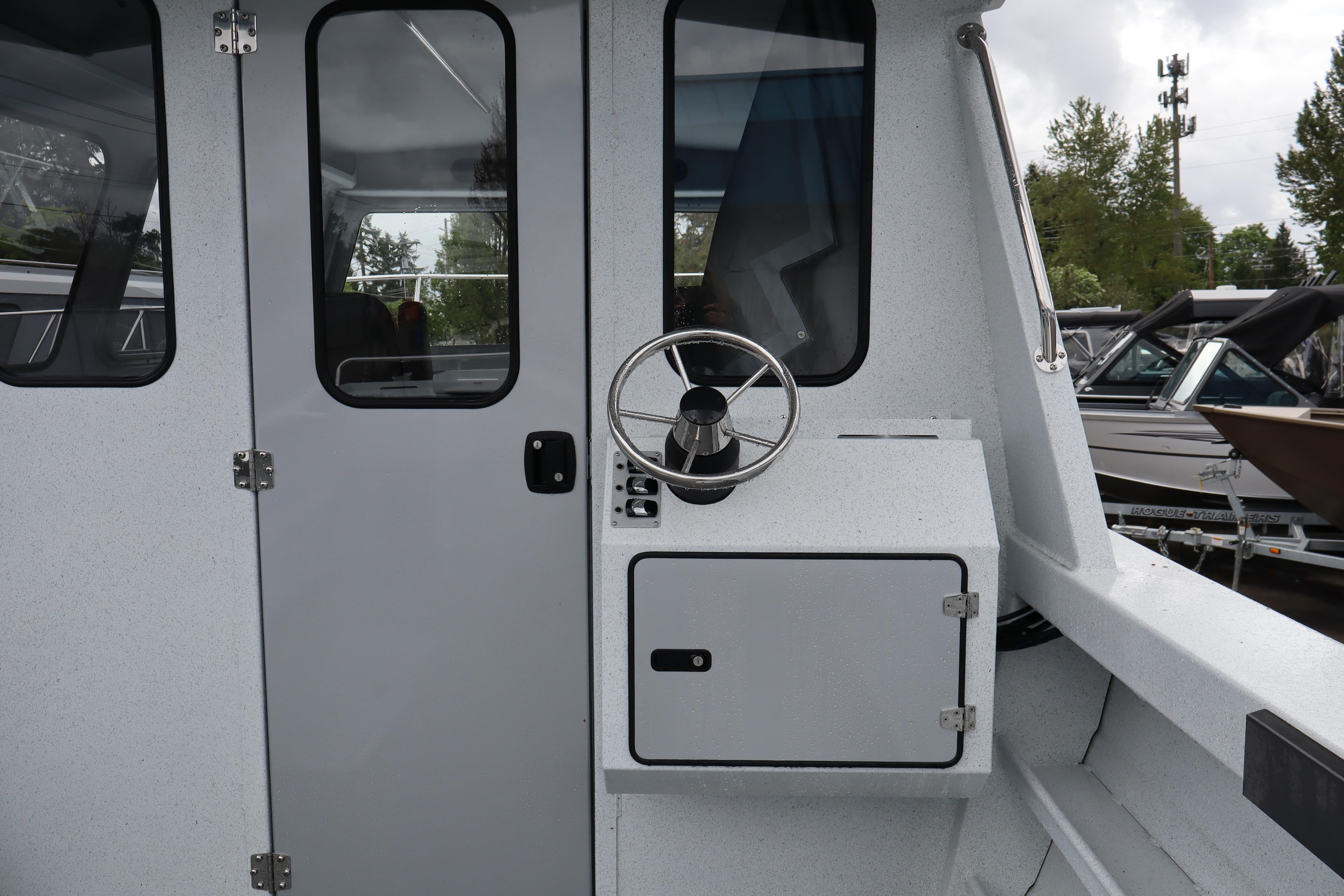 2026 KingFisher 2825 Coastal Express boat exterior with steering wheel and cabin door.