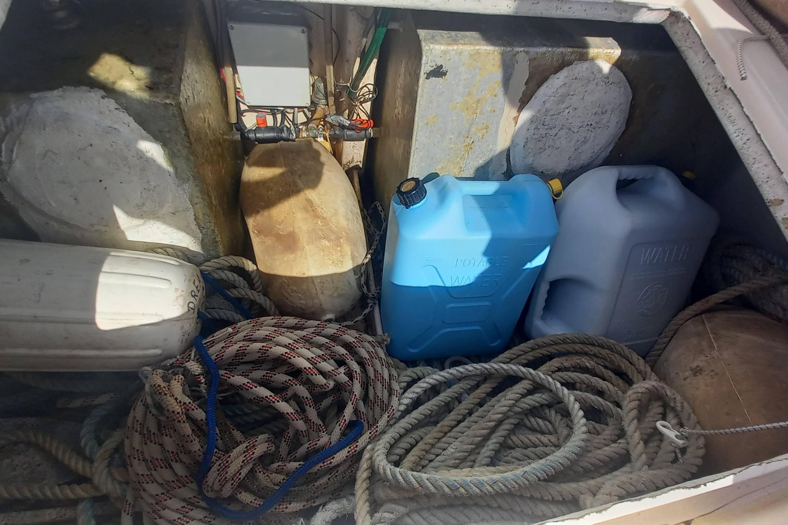 Storage compartment of 1993 Fountaine Pajot Antigua 37 with ropes and water containers.