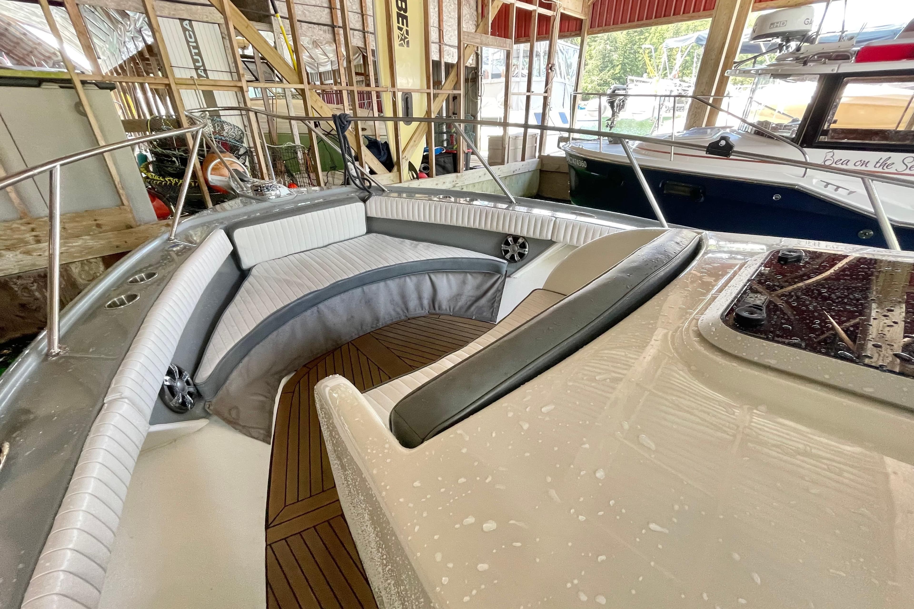 2017 Bertram 25 boat interior with cushioned seating and wooden flooring in a marina.