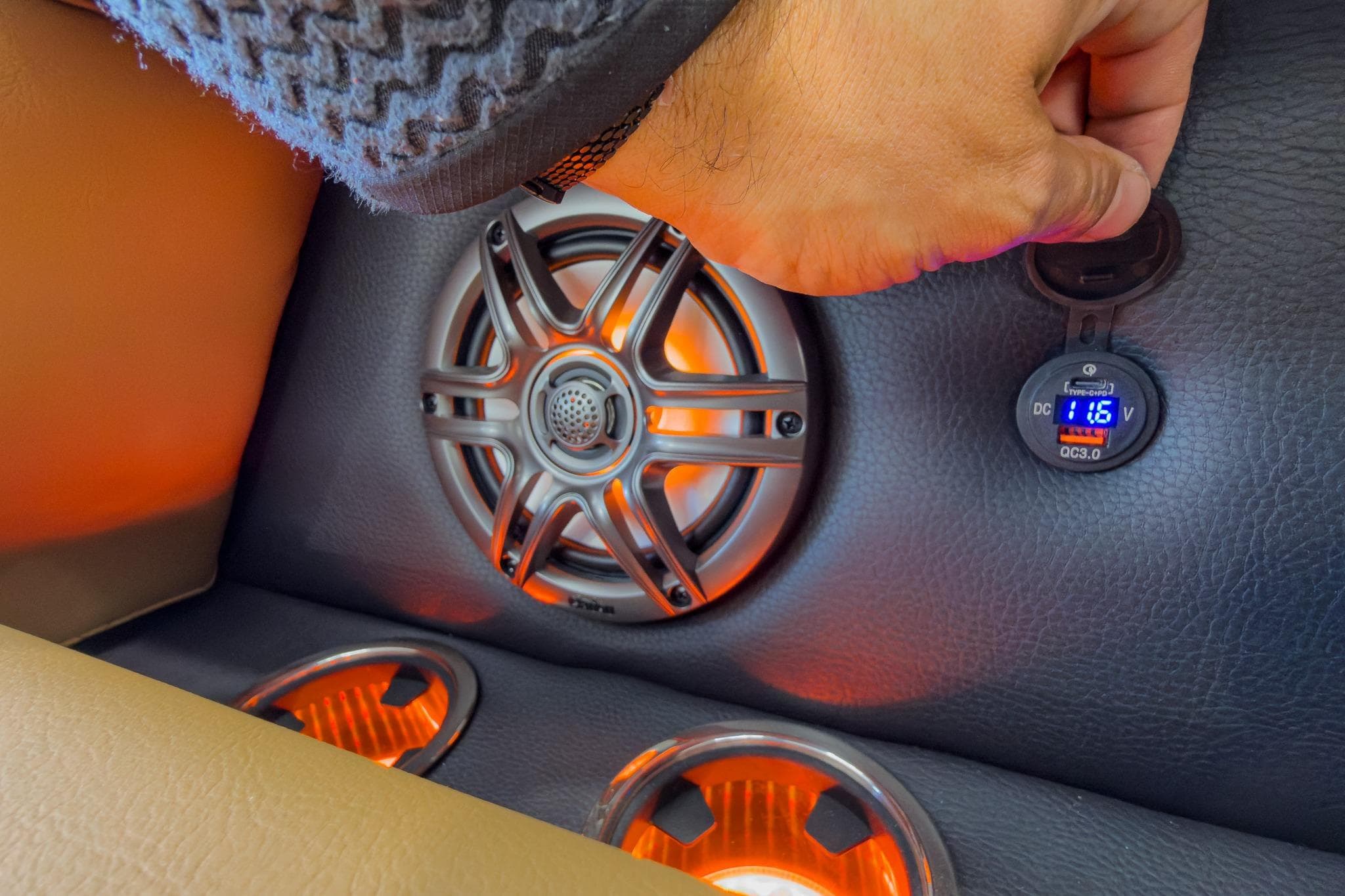 Hand adjusting speaker settings on 2026 Godfrey Sweetwater Tritoon with illuminated cup holders.