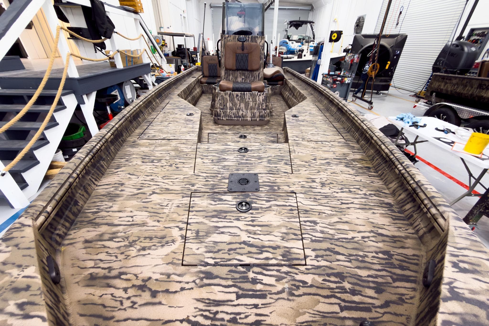 2026 Excel 220 Bay Pro Elite boat with camouflage design in a workshop setting.