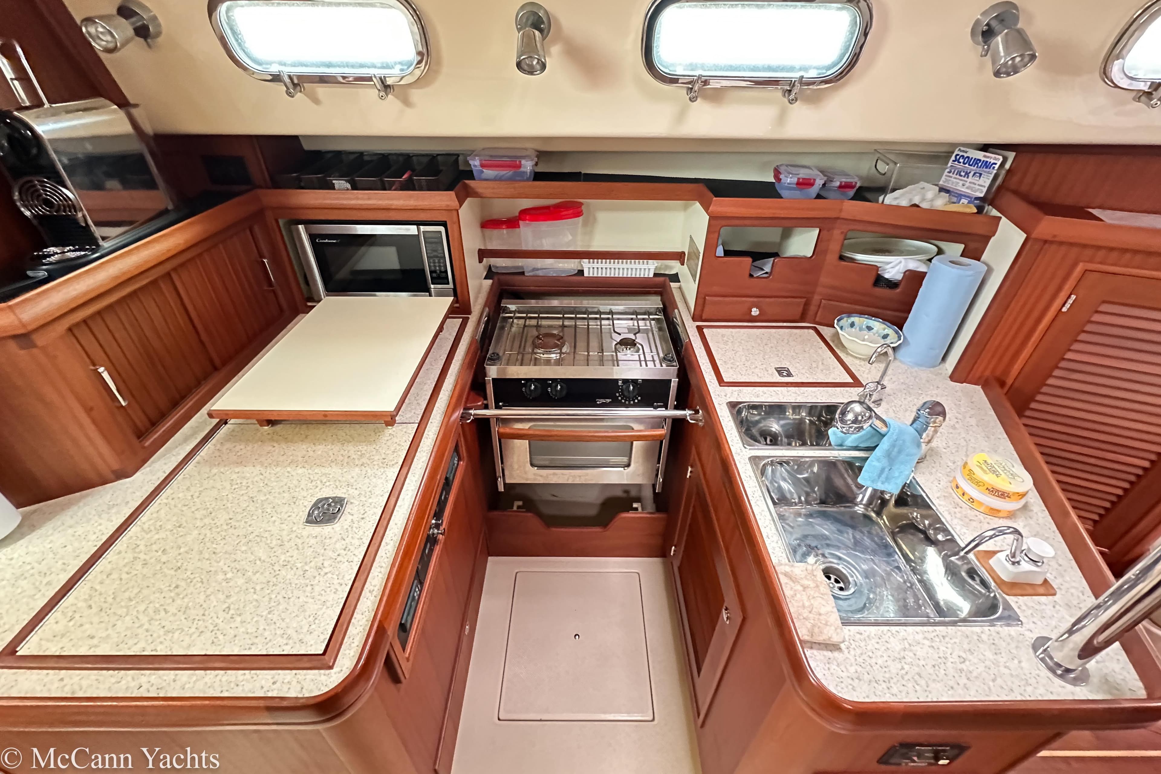 2010 Island Packet Estero yacht kitchen with stove, sink, and microwave in a compact layout.