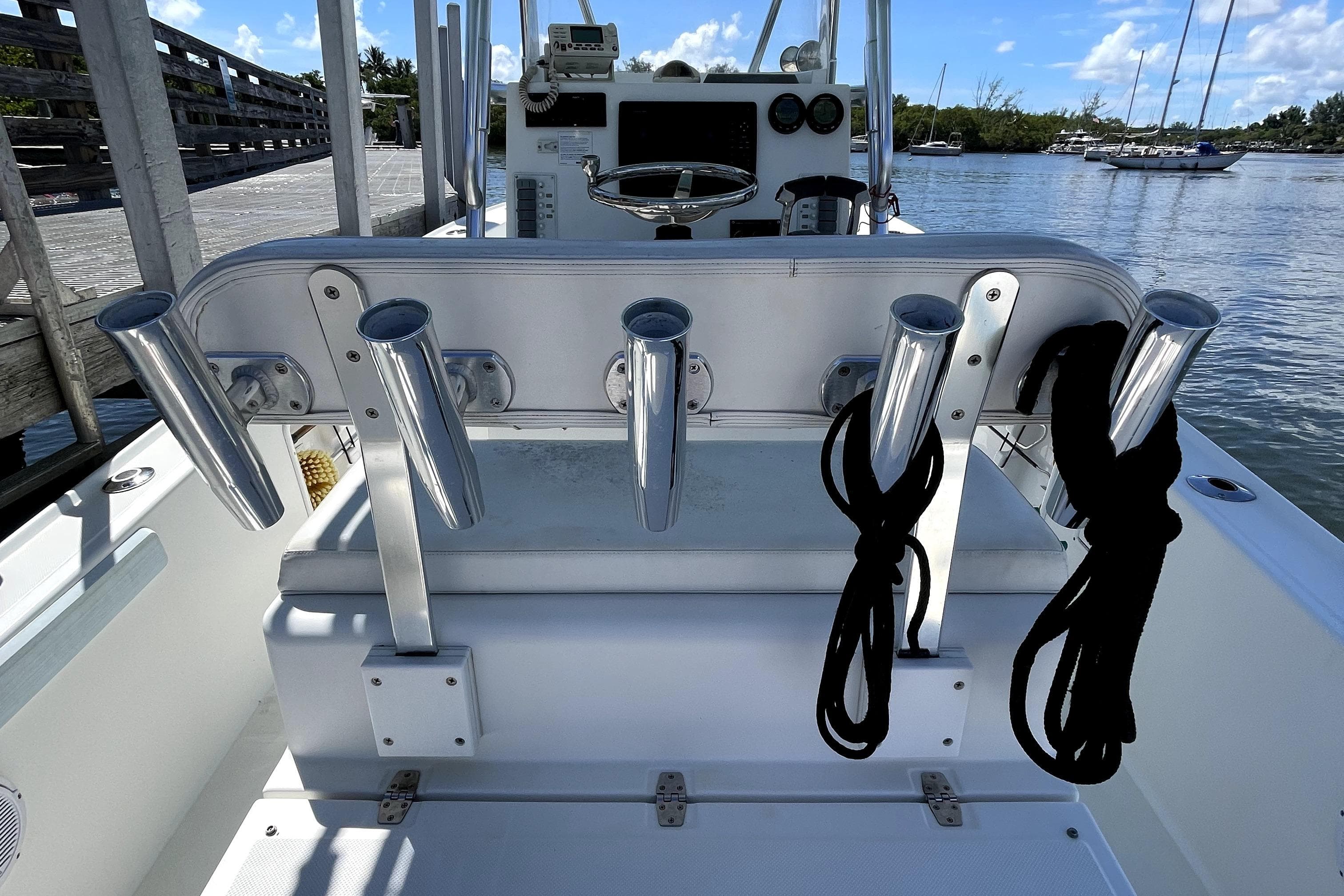 2013 Ocean Master 27 Center Console boat with rod holders and ropes, docked by the water.