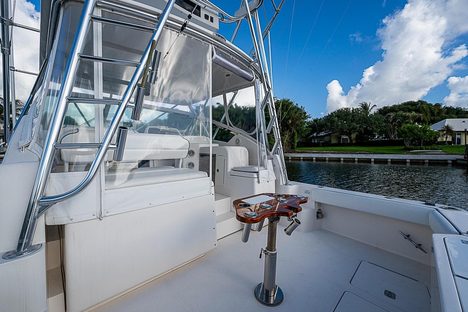 2008 Bertram 360 boat deck with seating and fishing rod holders, docked by a canal.