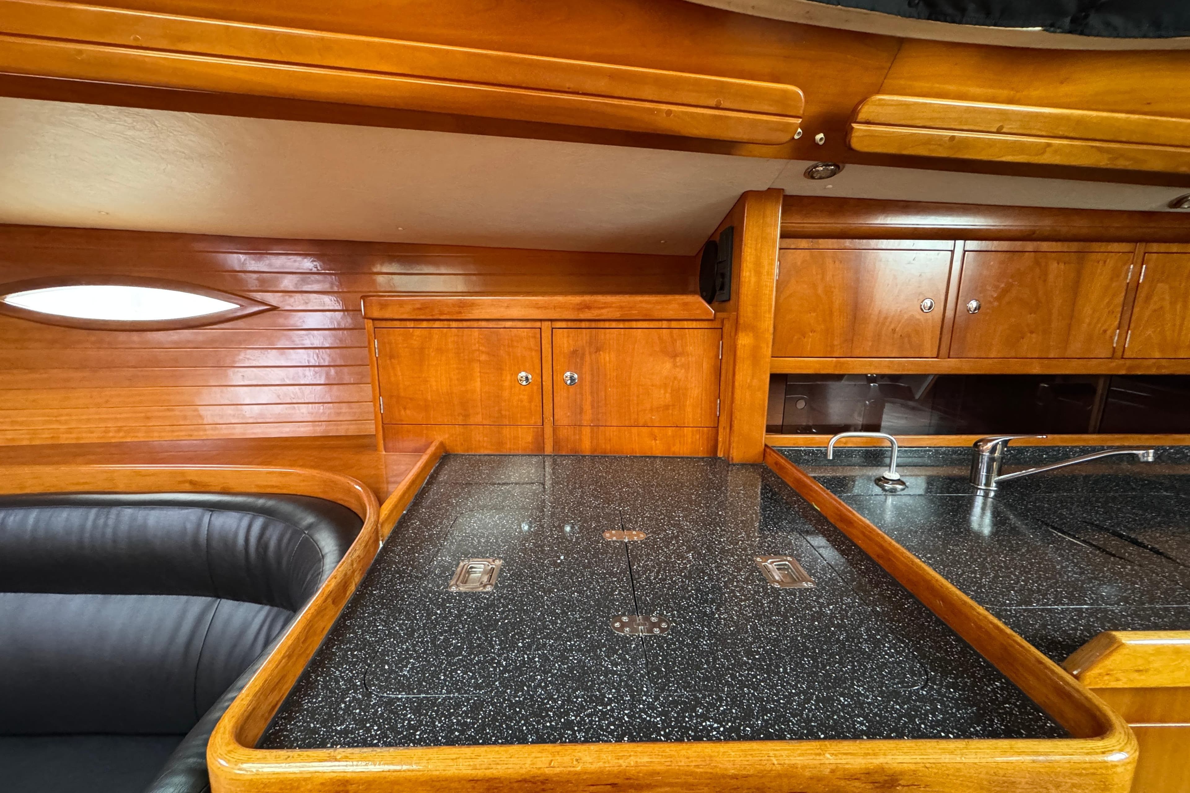 Interior of 2004 Alliaura FEELING 44 DI yacht with wood cabinetry and black countertop.